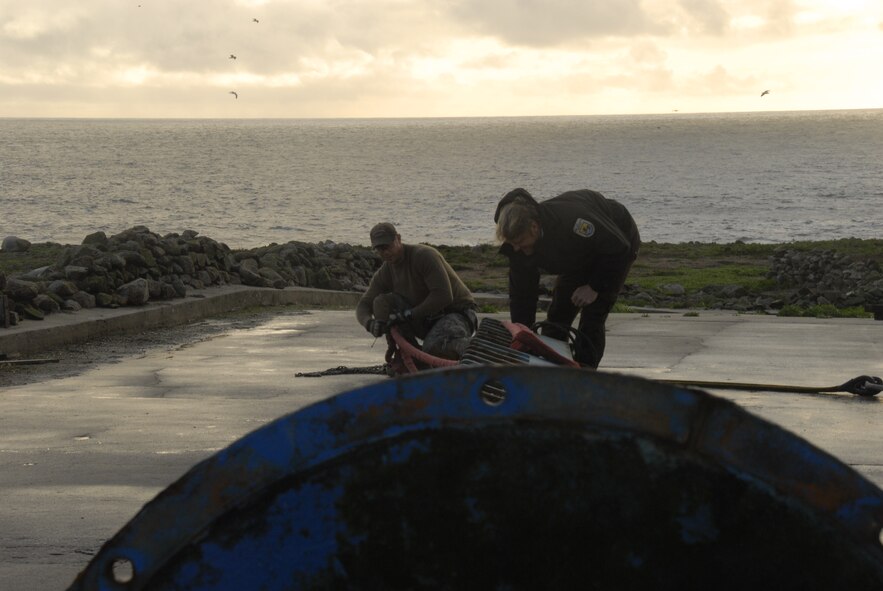 Chief Master Sgt. Rich Nowaski, HH-60G Pave Hawk flight engineer from the 129th Rescue Wing, and Zach Coffman, North Bay Refuges assistant manager, prepare to attach a cargo sling to pieces of a Farallon National Wildlife Refuges' boat crane Dec 21. The unit supported the U.S. Fish and Wildlife Service by transporting crane pieces to nearby Stinson Beach. (Air National Guard  photo by Airman 1st Class Jessica Green)