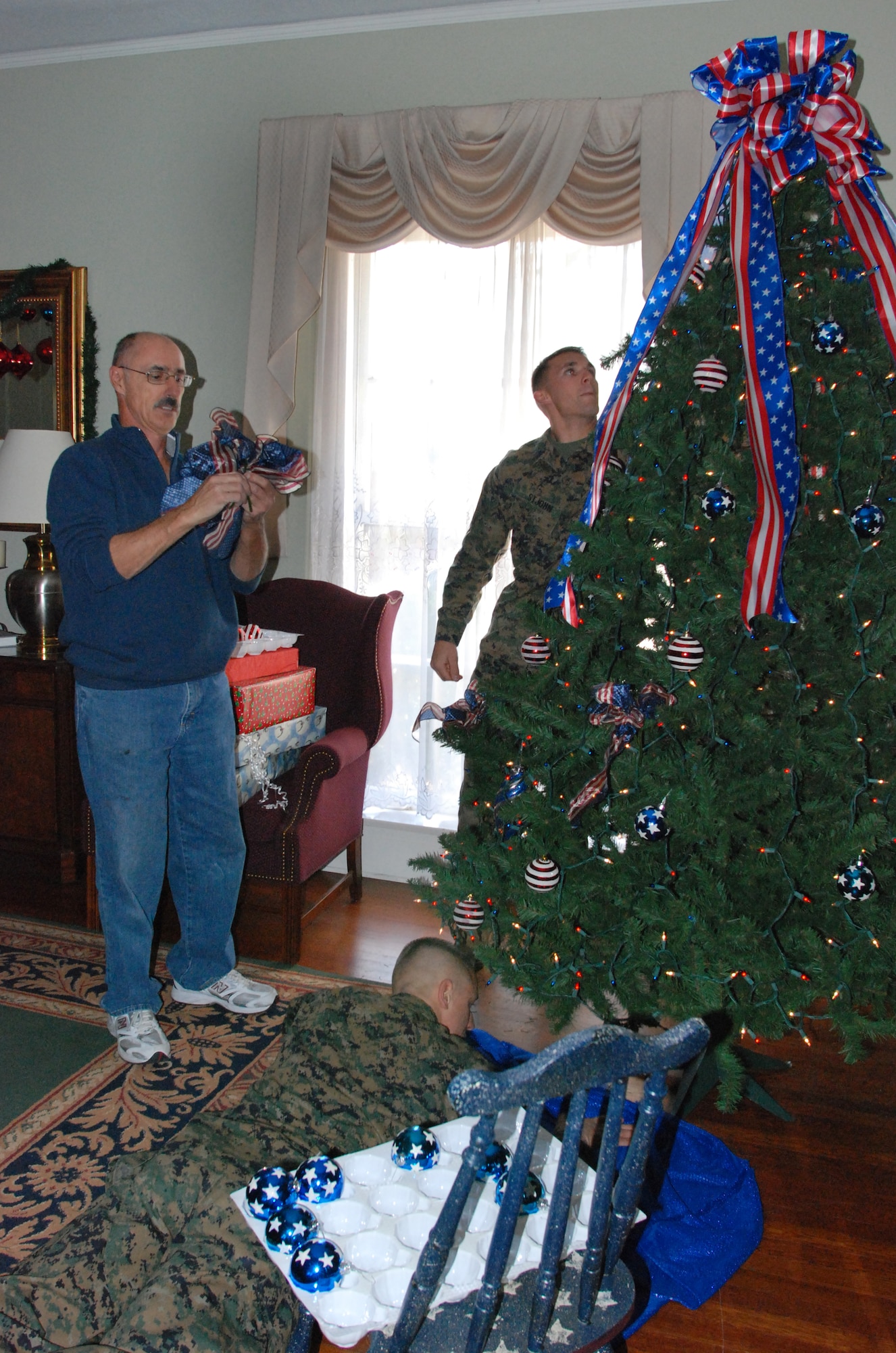 Lawrence Froehlich ties a bow for a Christmas tree in the Hap Arnold House while Marines from the Deployment Hangar hang ornaments. Volunteers decorated the house for the annual wing commander’s holiday reception and a dinner for Team March members who will be working on Christmas. (U.S. Air Force photo by Staff Sgt. Megan Crusher)