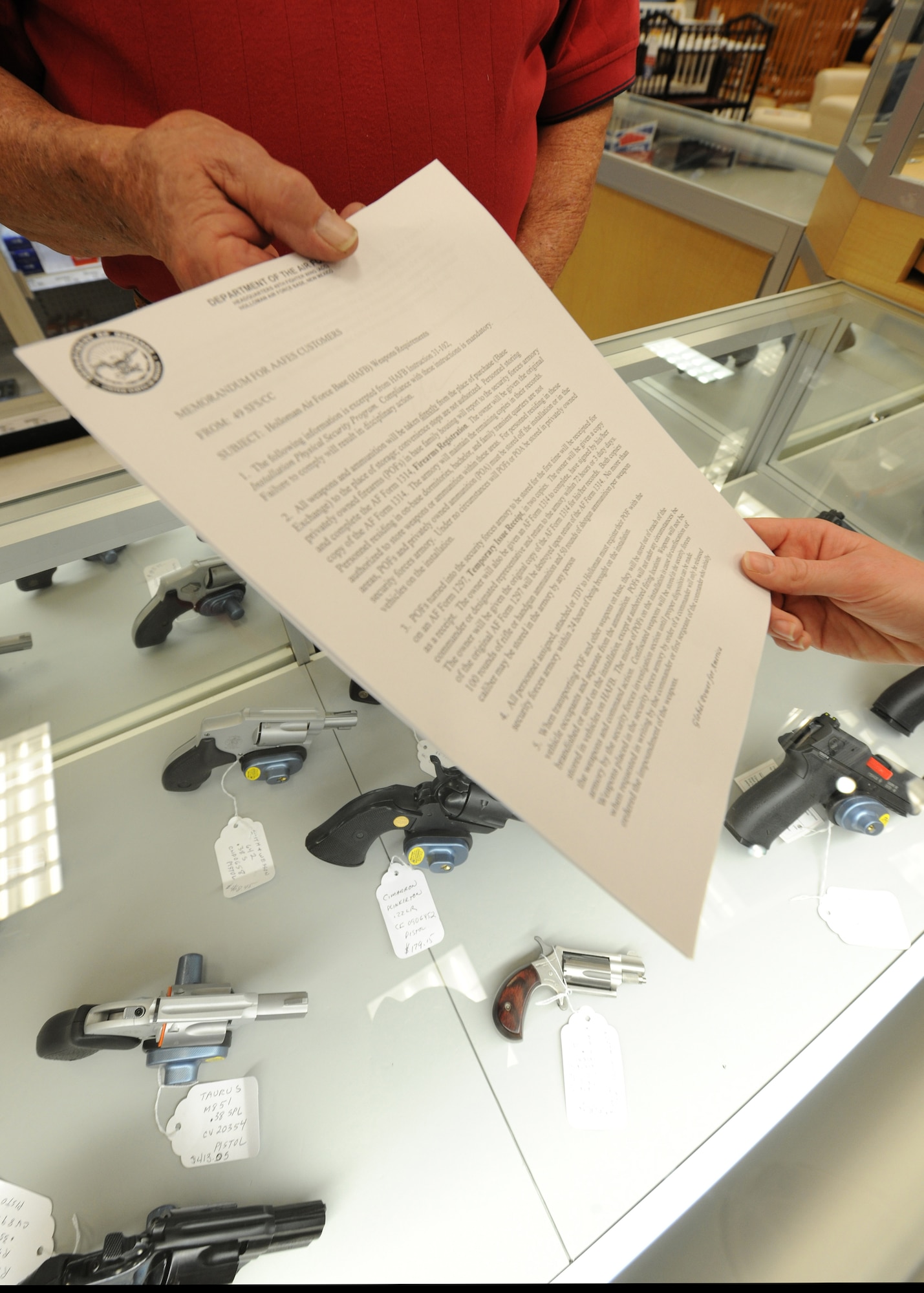 HOLLOMAN AIR FORCE BASE, N.M. -- An Army and Air Force Exchange Service firearms and ammunition employee hands out a copy of the 49th Security Forces Squadron commander's memorandum to a customer at the Base Exchange, Dec. 18. The memorandum is given and explained to all customers purchasing a firearm. Holloman Air Force Base Instruction 31-102, Installation Physical Security Program, states the policy in place for all members of Team Holloman and compliance to these instructions is mandatory. (U.S. Air Force photo by Senior Airman Michael Means)
