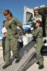 Members of the Florida Advanced Surgial and Transport Team Sally Noriega (left) and George Delgado (back) remove a patient from a patient evacuation vehicle with the help of fellow FAST Team members. 