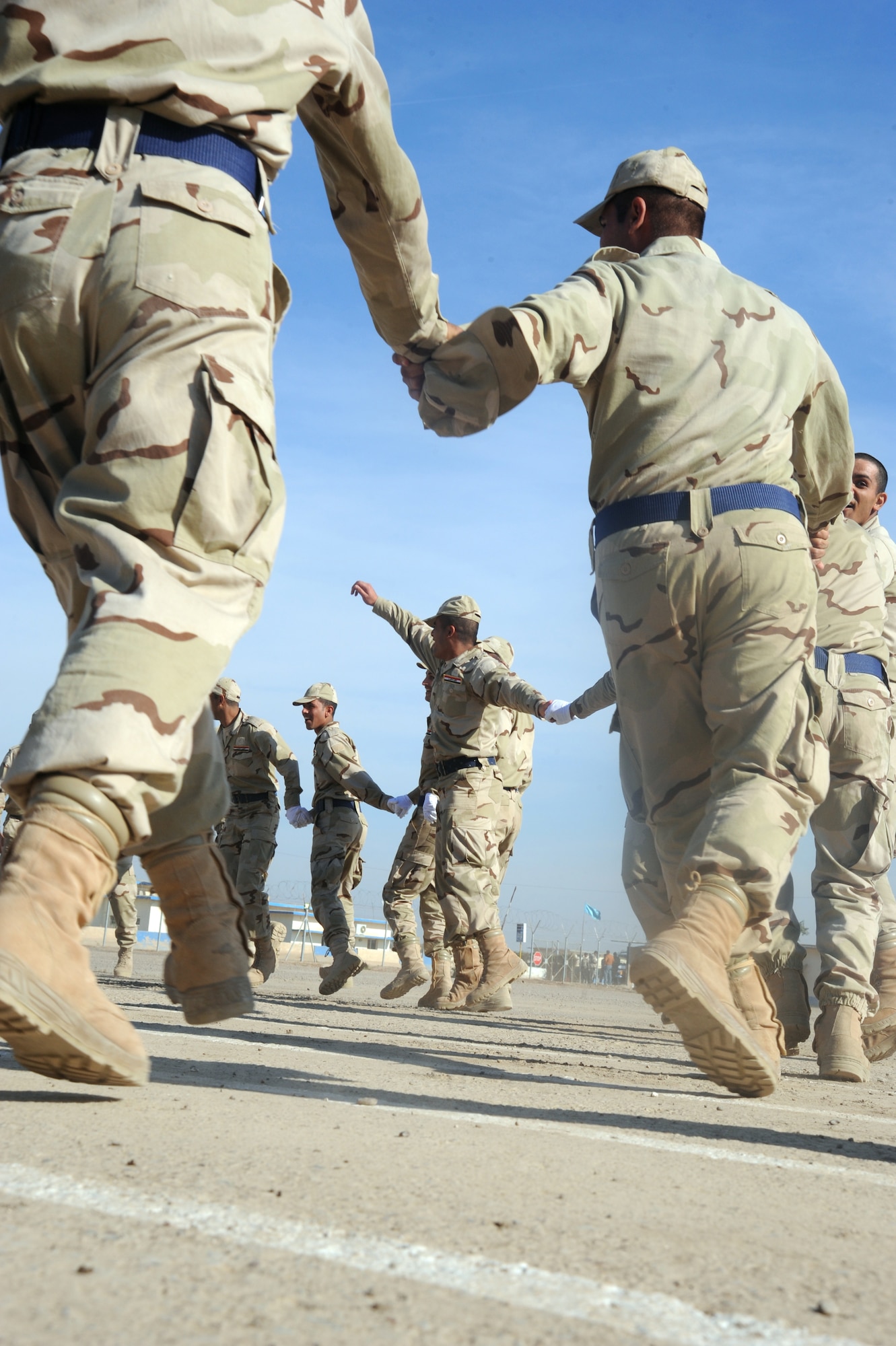 CAMP TAJI, Iraq -- Iraqi air force recruits celebrate with singing and dancing after their graduation from the basic military training Top Off course at the Iraqi Air Force Training School Dec. 28, 2009. The Top Off course teaches recruits about rank structure, leadership and what kind of benefits they will receive. (U.S. Air Force photo/Master Sgt. Trish Bunting)