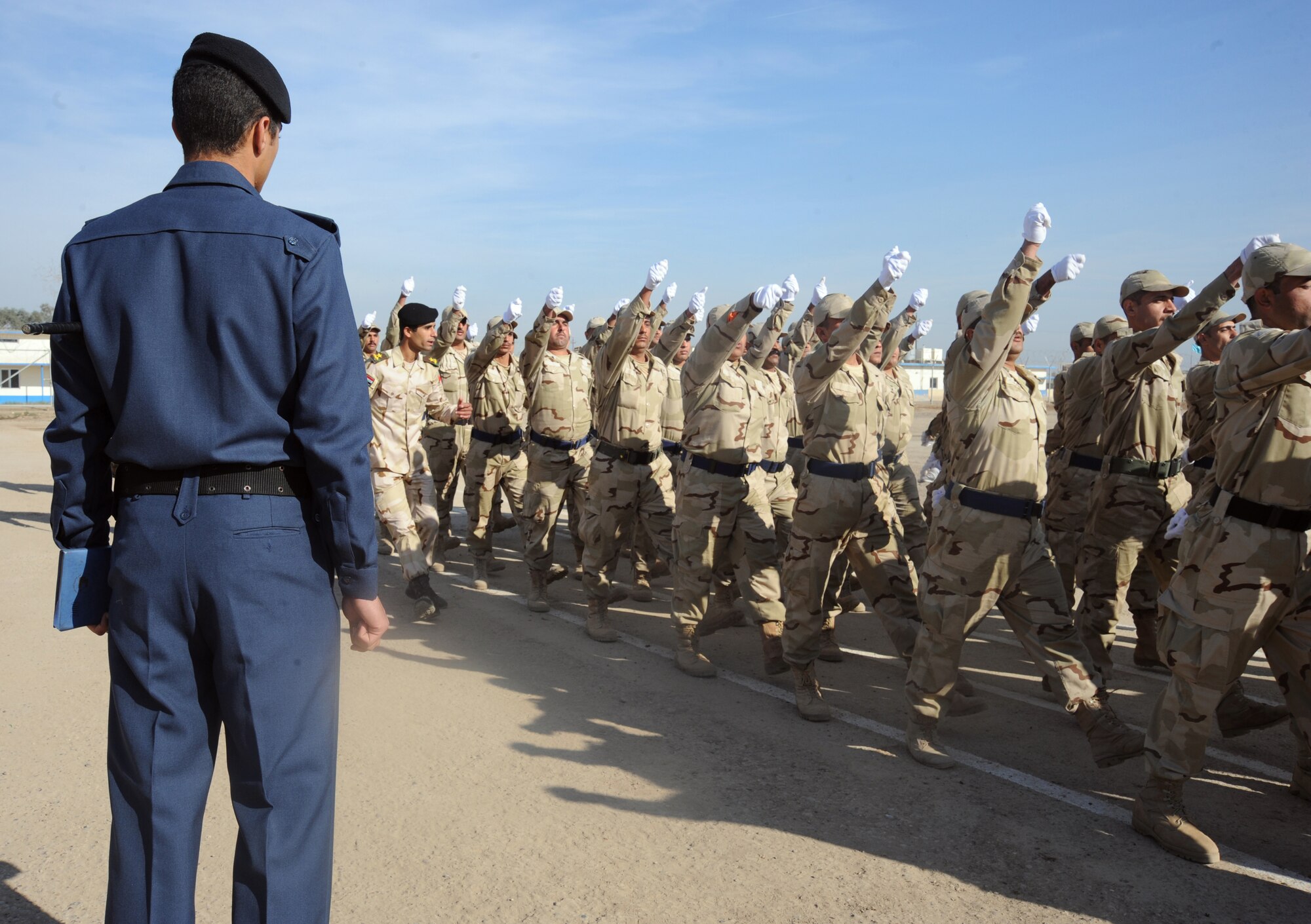 CAMP TAJI, Iraq -- An Iraqi air force training instructor observes new recruits marching in a pass in review parade at their graduation ceremony from the basic military training Top Off course at the Iraqi Air Force Training School Dec. 28, 2009.  The staff incorporated discipline, marching, and drill during the morning sessions and academics in the afternoon. (U.S. Air Force photo/Master Sgt. Trish Bunting/Released)