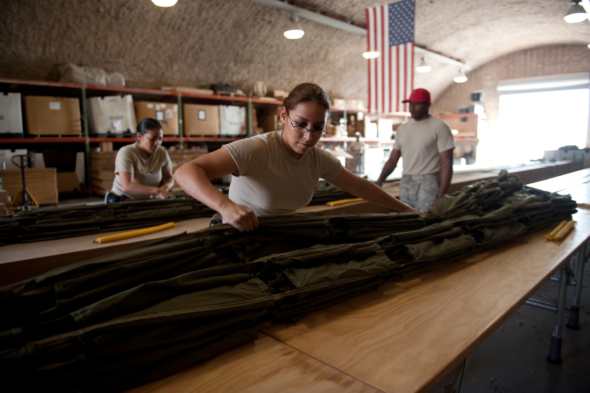 Center, U.S. Army Pfc. Amanda Regalado, 824th Quarter Master Company Heavy Airdrop Supply Detachment 8, packages a parachute in preparation for an airdrop, Dec. 29, 2009, in Southwest Asia. Pfc. Regalado helps with air drop shipments delivered to military service members in Southwest Asia in support of Operations Iraqi and Enduring Freedom. (U.S. Air Force photo/Staff Sgt. Robert Barney/RELEASED) 