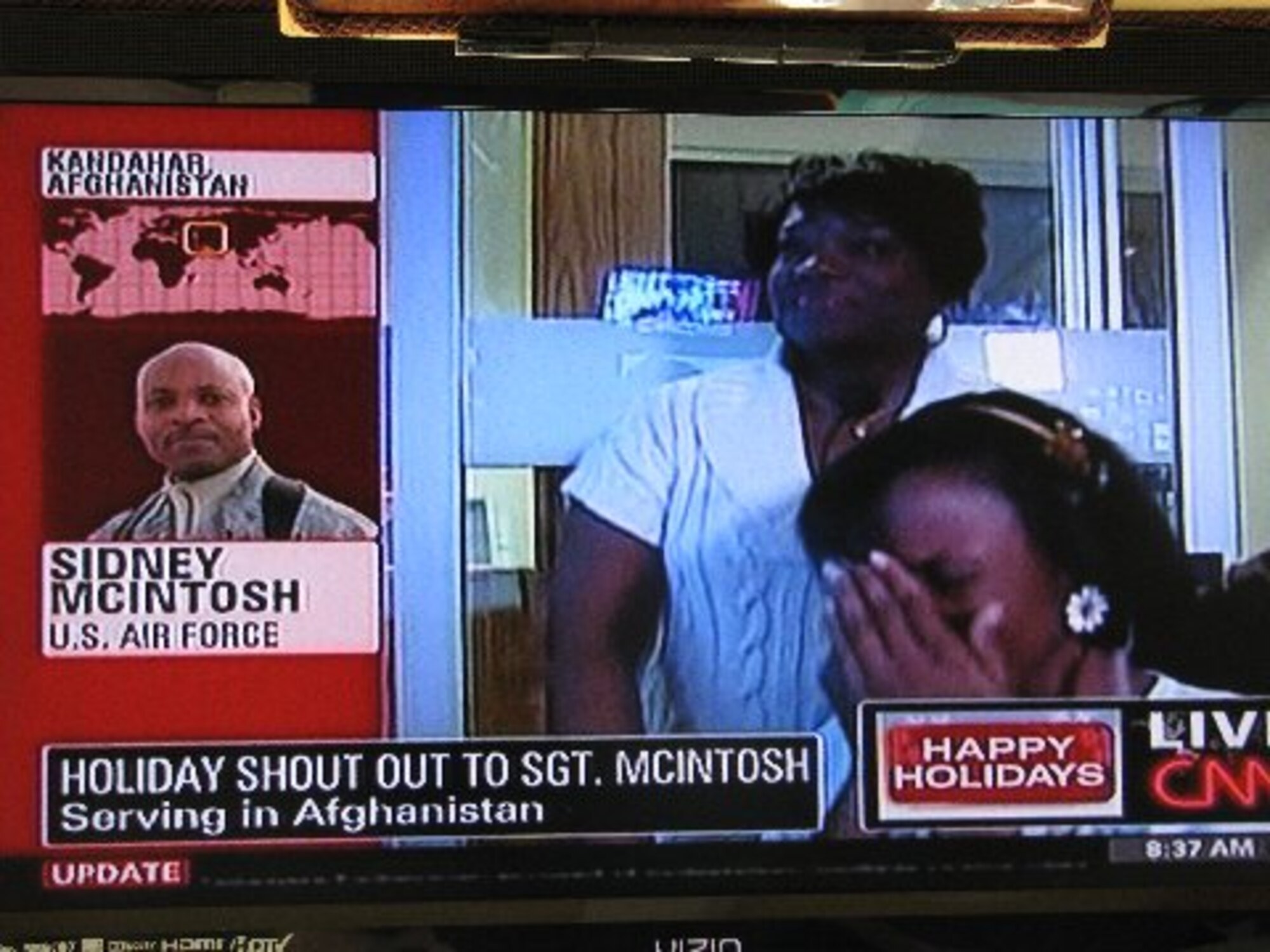 KANDAHAR AIRFIELD, Afghanistan -- During a surprise live telephone interview on national television for his daughter, Senior Master Sgt. Sidney McIntosh, 451st Expeditionary Mission Support Group Manpower Superintendent, wishes Sydney McIntosh a Merry Christmas on CNN News Dec. 25 as his wife, Michelle McIntosh, stands by her side.  Sydney is an Associate Producer for the CNN Newsroom show anchored by Tony Harris.  (Courtesy photo)
