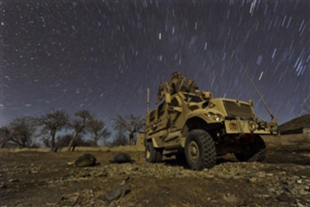 U.S. Army Pfc. Brent Dawkins (left) and U.S. Air Force Tech. Sgt. Efren Lopez sleep on the ground beside a mine-resistant, ambush-protected vehicle while snow falls in Wam Valley, Kandahar province, Afghanistan, on Dec. 22, 2009.  