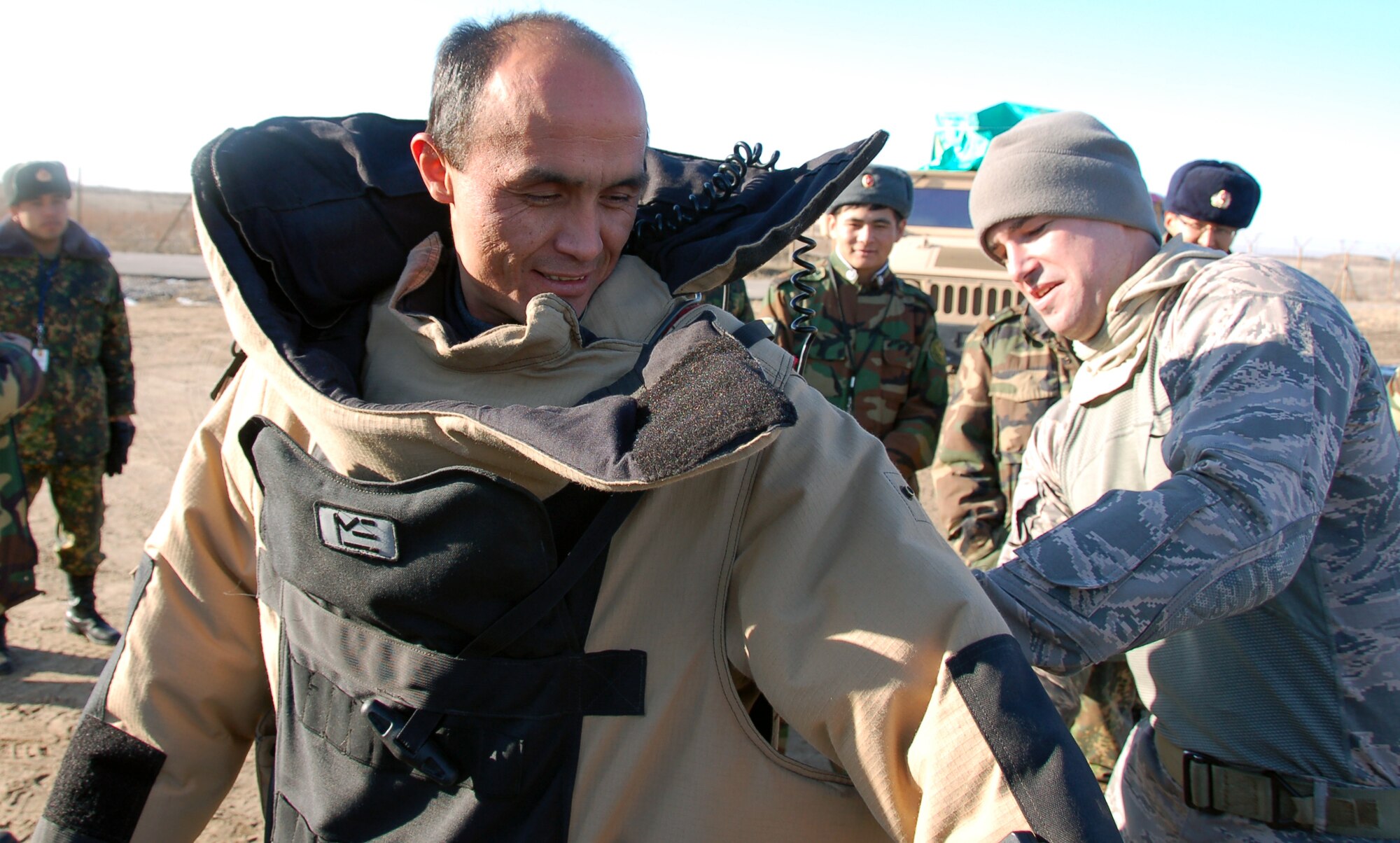 TRANSIT CENTER AT MANAS, Kyrgyzstan - Tech. Sgt. Joseph Deslauriers, EOD technician with the 376th Expeditionary Civil Engineer Squadron, assists Kyrgyz Lt. Col. Kadyrov Almazbek with putting on an explosive ordnance disposal protection suit during the Kyrgyz Ministry of Defense team’s visit to learn about EOD operations from Airmen here Dec. 15, 2009. The five-day visit, which enabled the Kyrgyz team get a close-up look at various EOD equipment, was to help the host nation build its EOD team.  (U.S. Air Force photo/Staff Sgt. Olufemi Owolabi)