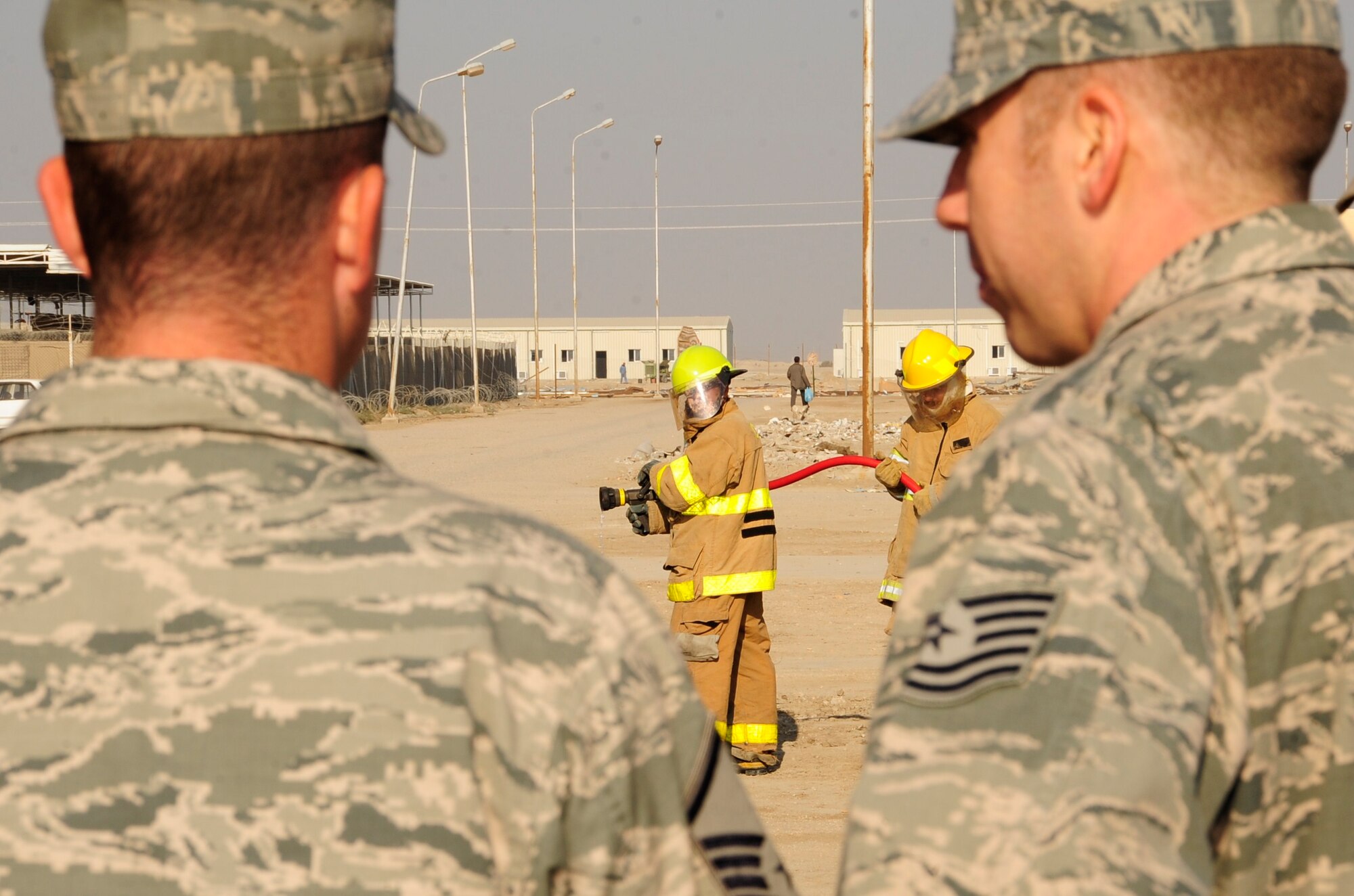 CAMP UR, Iraq - Master Sgt. Christopher Sparks, and Tech. Sgt. Matthew Peay, 407th Expeditionary Civil Engineer Squadron fire department, look on during an exercise by Iraqi firefighters, Dec. 28, 2009.  The Airmen provide training to the Iraqi Army fire department three times a week to ensure Iraqi firefighters are self sufficient.  (U.S. Air Force photo/Master Sgt. Darrell Habisch) 