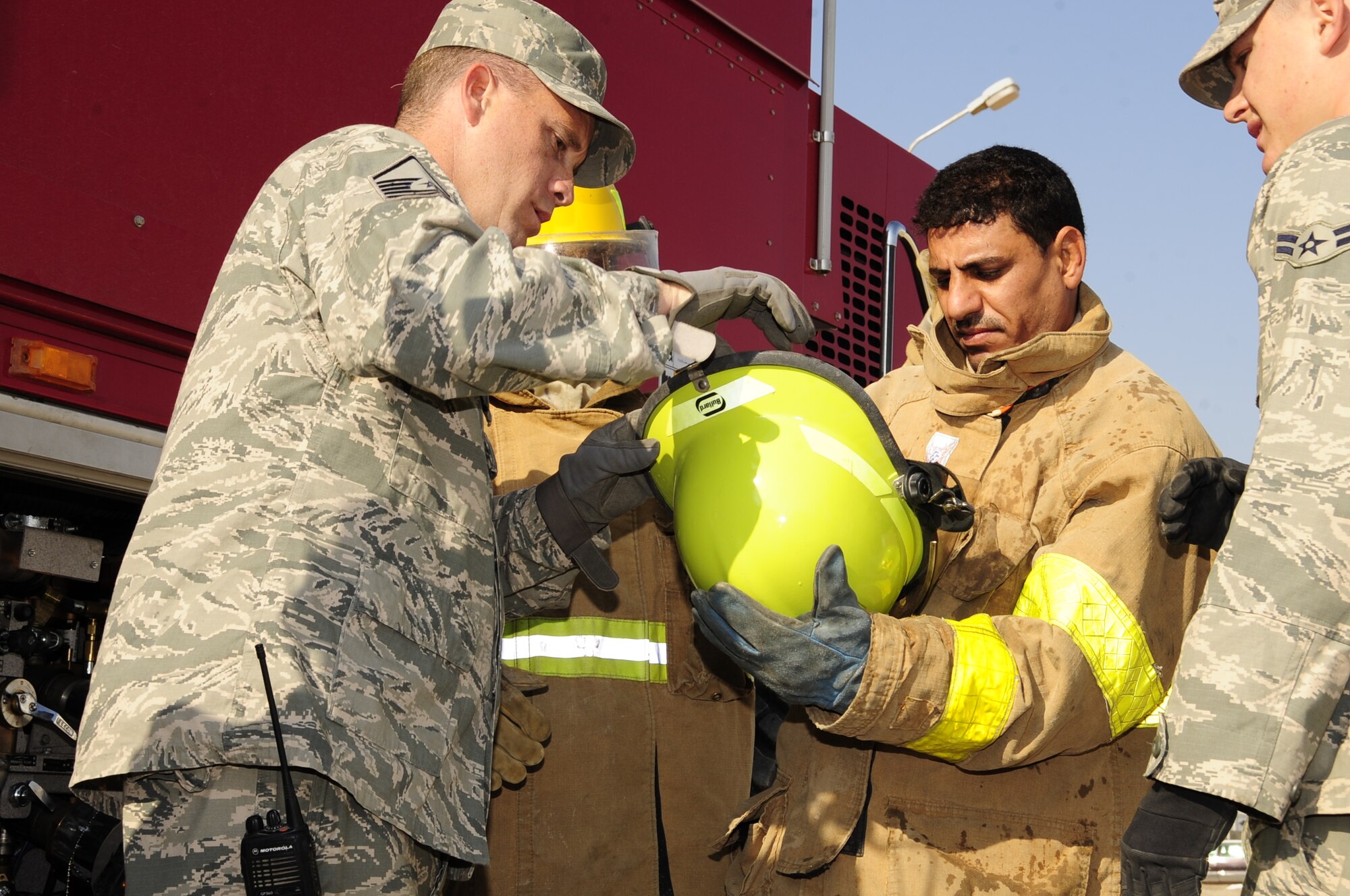 CAMP UR, Iraq - Master Sgt. Christopher Sparks, 407th Expeditionary Civil Engineer Squadron fire department, instructs an Iraqi firefighter on proper wear of personal protective equipment before a fire training exercise, Dec. 28, 2009.  The Airmen provide training to the Iraqi Army fire department three times a week to ensure Iraqi firefighters are self sufficient.  (U.S. Air Force photo/Master Sgt. Darrell Habisch) 