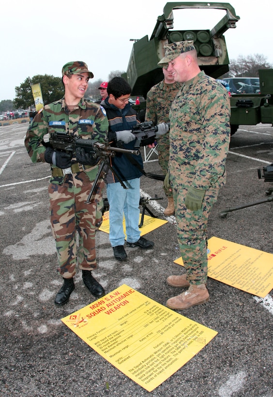Marine Lance Cpl. Justin Roberts (right) explains the functioning of the M249 Squad Automatic Weapon to Rodney Johnson at the Armed Forces Bowl "Adventure Zone" prior to the football game at the Texas Christian University campus here Dec. 31,2009.  Roberts, a water well driller from Glen Rose, Texas in his civilian career, is an electro-optical ordnance technician with Headquarters Battery, 14th Marine Regiment, Marine Forces Reserve.   Johnson, 14, is a cadet in the Civil Air Patrol.