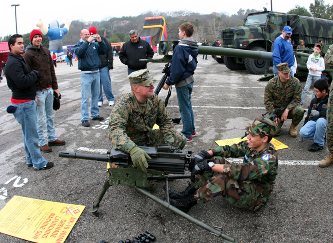 Lance Cpl. Justin Roberts (left) explains the functioning of the MK-19 grenade launcher to 14-year-old Civil Air Patrol Cadet Rodney Johnson at the Armed Forces Bowl 'Adventure Zone' prior to the football game at the Texas Christian University campus here Dec. 31, 2009.  Roberts is an electro-optical ordnance technician with Headquarters Battery, 14th Marine Regiment, 4th Marine Division.