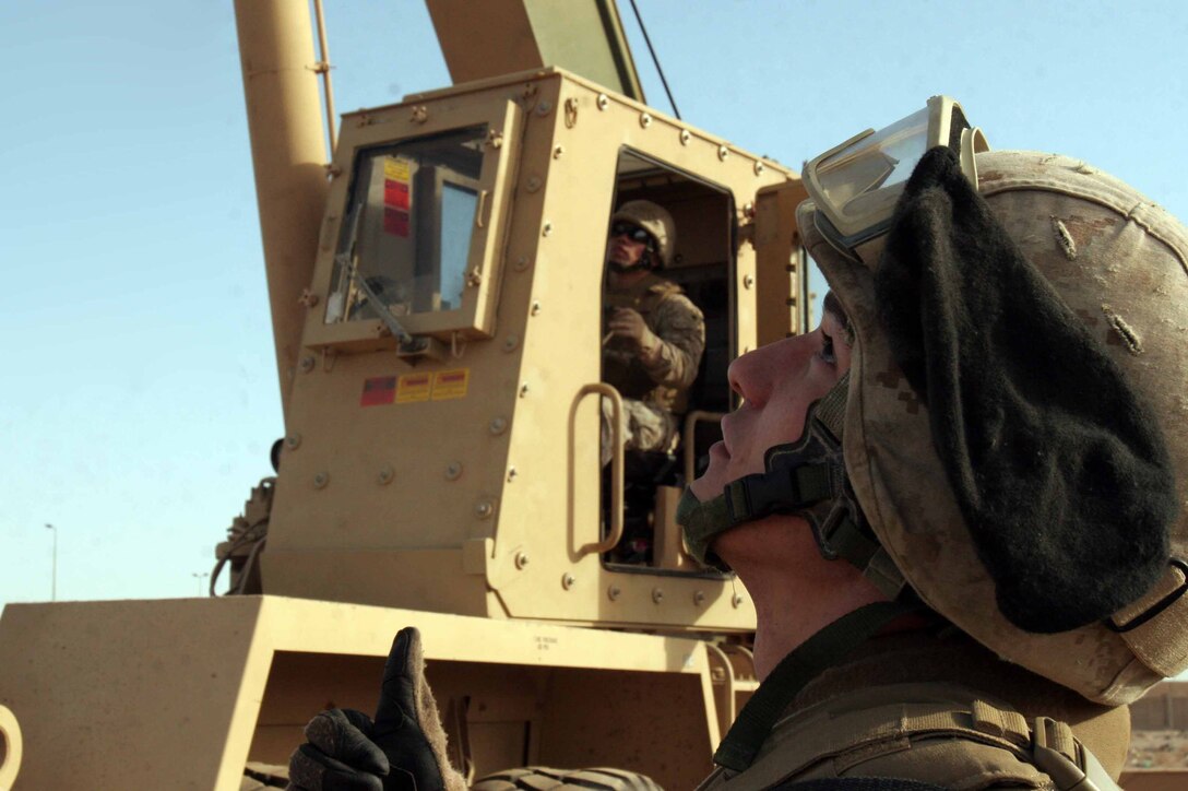 Cpl. Justin S. McBride, a native of Guthrie, Okla., and a heavy equipment operator with Heavy Equipment Platoon, Combat Logistics Company 51, Combat Logistics Battalion 5, 2nd Marine Logistics Group, guides Galveston, Texas native Sgt. Raymond Reyes, the platoon sergeant of HE Platoon, as he positions a crane. The Marines were taking part in a combined de-militarization operation of Entry Control Point International, AR Ramadi, Iraq, with 2nd Battalion, 9th Marine Regiment.