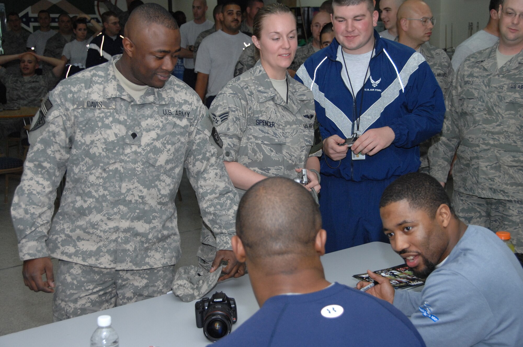 SOUTHWEST ASIA -- National Football League players, Sammy Mooris and Josh Wilson, discuss football teams with each other while signing autographs for the troops at an air base in Southwest Asia, Jan. 31. Morris and Wilson are currently on a U.S. Army Super Sunday Tour along with Willie Roaf, New Orlean Saints,and three Raiderette cheerleaders. (U.S. Air Force photo/Senior Airman Courtney Richardson)
