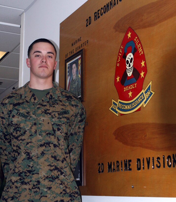 Lance Cpl. Bryan Vasquez, a 21-year-old from Orange County, Calif., and a reconnaissance Marine with 2nd Reconnaissance Battalion, 2nd Marine Division, stands proudly in front his photograph inside the 2nd Recon Bn. headquarters Feb. 2.  Vasquez recently won the Division Marine of the Quarter award.  Vasquez said he was surprised to be nominated for the award and was honored to actually win.  (Official U.S. Marine Corps photo by Lance Cpl. Casey Jones) (RELEASED)