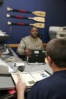 Staff Sgt. Leroy Clemons speaks with Joedy Petit in his cubicle, a feature of the new office design, Feb. 2 at Recruiting Substation K-Metro, Recruiting Station Kansas City. JWT, the Marine Corps’ advertising firm, has worked to create a new uniformed interior design for the offices consistent with the image created for the Corps’ Web, print and television campaigns. Clemons is a recruiter and Petit is a poolee apart of the delayed entry program at K-Metro.