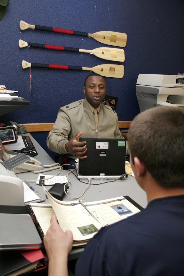 Staff Sgt. Leroy Clemons speaks with Joedy Petit in his cubicle, a feature of the new office design, Feb. 2 at Recruiting Substation K-Metro, Recruiting Station Kansas City. JWT, the Marine Corps’ advertising firm, has worked to create a new uniformed interior design for the offices consistent with the image created for the Corps’ Web, print and television campaigns. Clemons is a recruiter and Petit is a poolee apart of the delayed entry program at K-Metro.