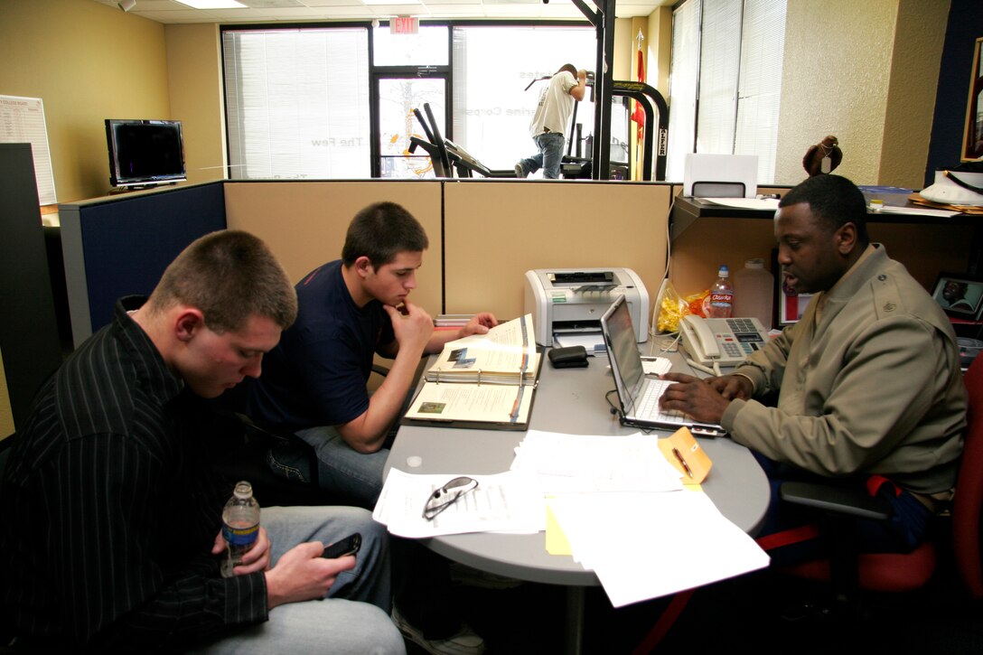 Staff Sgt. Leroy Clemons conducts a meeting with two of his poolees, Joedy Petit and Josh Wimsatt, while another potential poolee exercises in the office of Recruiting Substation K-Metro, Recruiting Station Kansas City Feb. 2. JWT, the Marine Corps’ advertising firm, has worked to create a new uniformed interior design for the offices consistent with the image created for the Corps’ Web, print and television campaigns. Clemons is a recruiter at K-Metro.