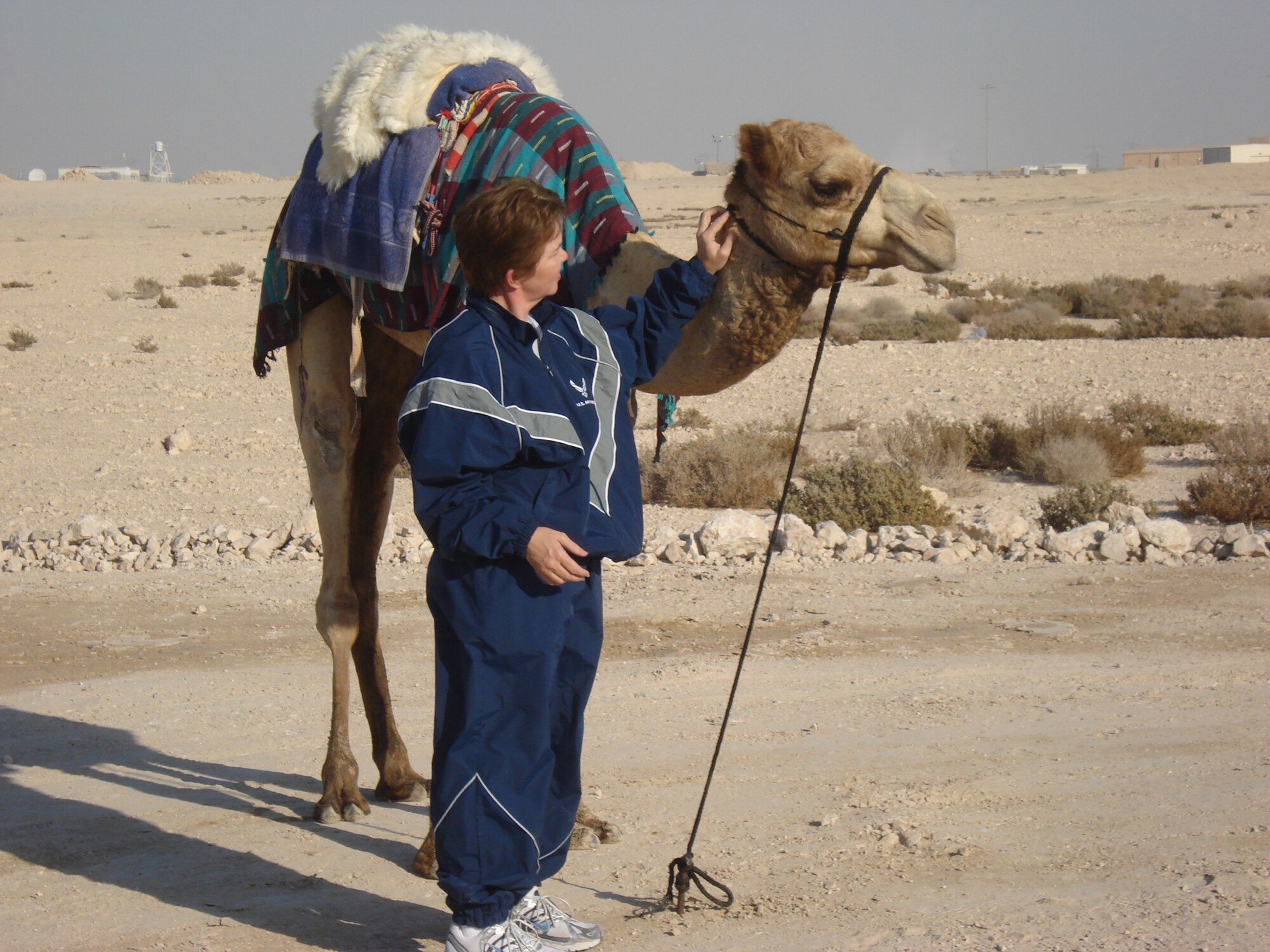 Maj. Martha Kuder tries to "convince a camel (they are) friends" before she sits on its saddle above her. Major Kuder has been deployed to Southwest Asia since Septemember, 2009, as an executive officer for the 379th Expeditonary Operations Group. She will soon return to her civilian/military job as a performance manager for the 931st Air Refueling Group, an Air Force Reserve unit at McConnell Air Force Base, Kan. (Courtesy photo)