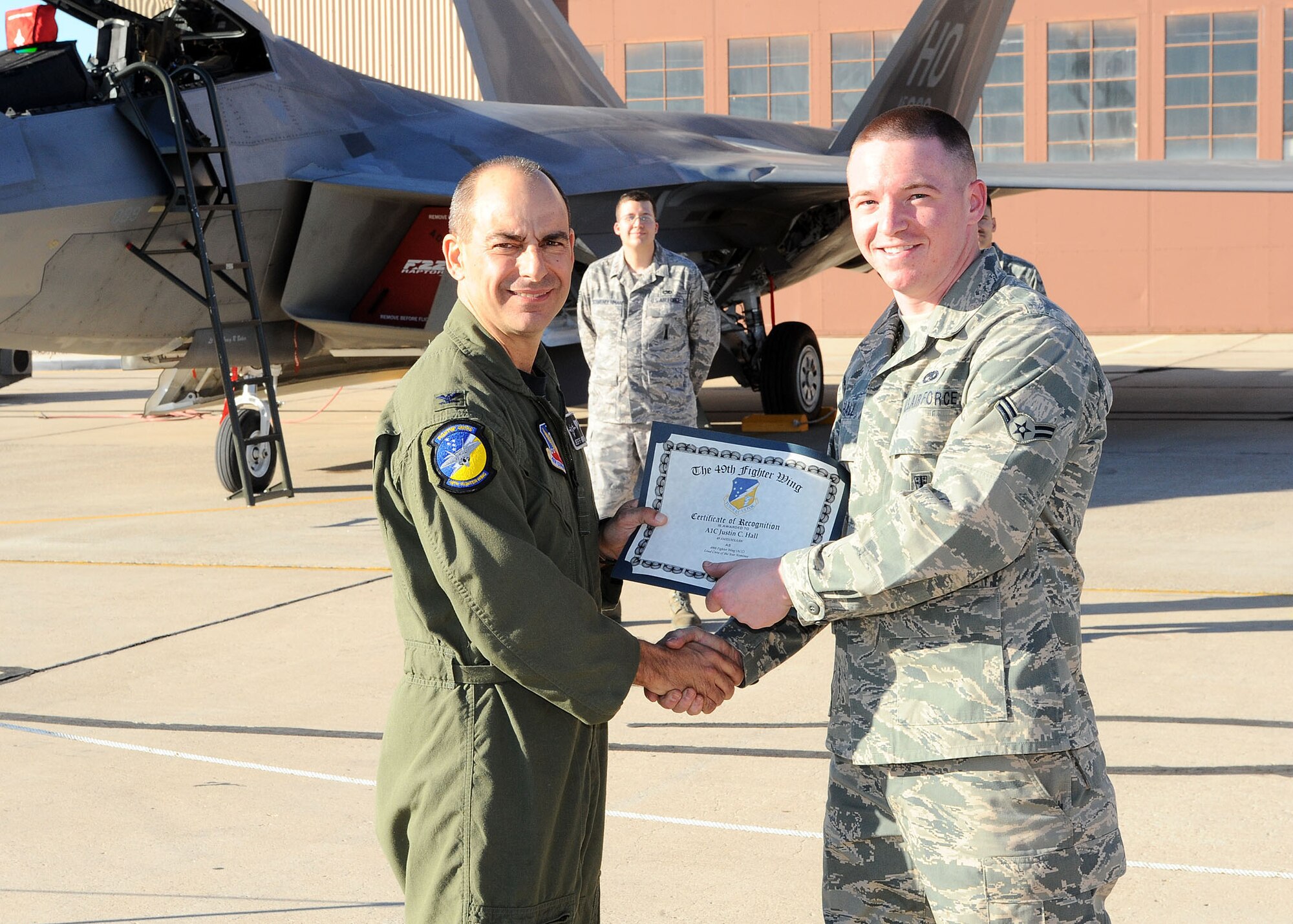 49th Fighter Wing commander, Col. Jeff Harrigian, presents a certificate of recognition to Airman 1st Class Justin Hall, 49th Aircraft Maintainance Squadron, at the Load Crew of the Year competition at Holloman Air Force Base, N.M., Jan. 30. Airman Hall was being recognized for the effort given at the competition. (U.S Air Force photo/ Airman 1st Class DeAndre Curtiss)