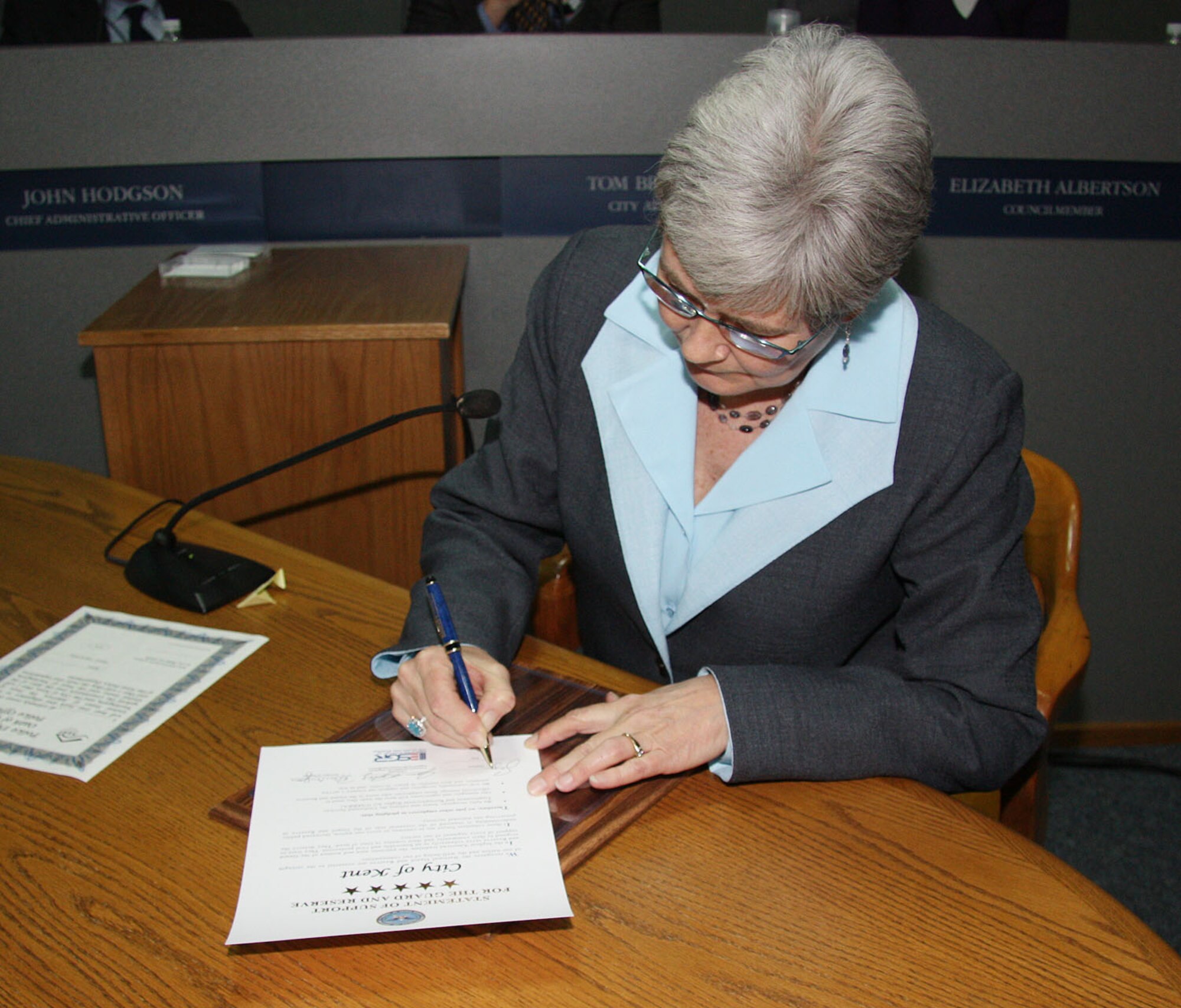 City of Kent Mayor Suzette Cooke signs a statement of support for the Guard and Reserve at a city council meeting Jan. 20.  Lt. Col. Ray Luevanos and Lt. Col. Martin Oliver are both Reservists in the 446th Airlift Wing and employees for the city. Both were present at the signing of the statement of support.  The statement of support confirms the city of Kent, Wash., pledges that they fully recognize, honor and enforce the Uniformed Services Employment and Re-Employment Rights Act. A majority of the Reservists assigned to the 446th Airlift Wing live and work in western Washington.  (Courtesy photo from the city of Kent)
