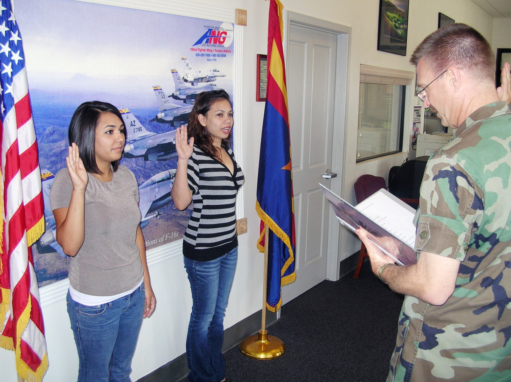 New 162nd Fighter Wing recruits, Vanessa Ferreira and Marie Ann Camara, are sworn in by Lt. Col. Michael Knutson at the base recruiting office. Both Airmen are non-prior service recruits. The recruiting office aims to ensure that at least 30 percent of all recruits are non-prior service. (Air National Guard photo by Senior Master Sgt. (ret.) Ira Zarin)