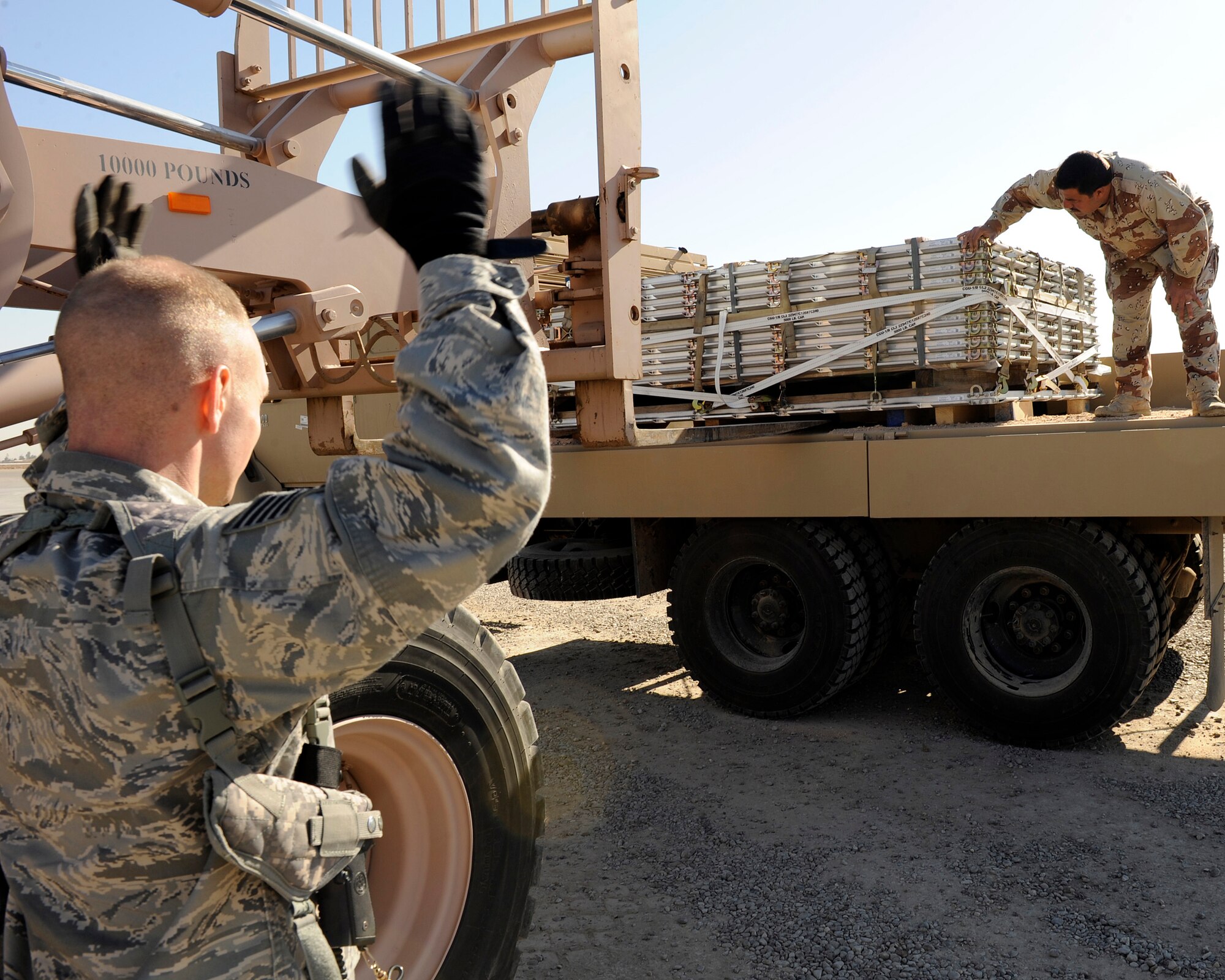 Tech. Sgt. Joshua Hodgin, from the 321st Air Expeditionary Advisory Group, and an Iraqi airman guide a forklift unloading pallets onto a trailer at Sather Air Base, Iraq, Jan. 23, 2009. The pallets are the first delivery to the Iraqi Air Force and are a test of the new logistical readiness system at the Iraqi Air Force?s new Al Muthana Air Base in Baghdad, Iraq. (U.S. Air Force Photo/Senior Airman Jacqueline Romero) 