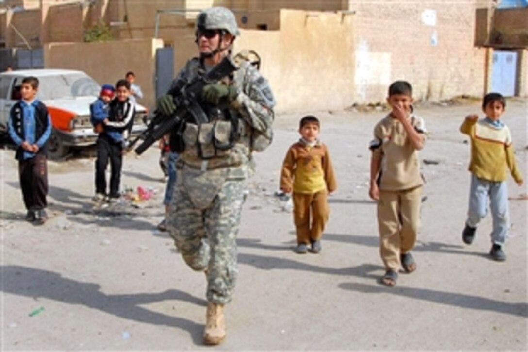 U.S. Army Sgt. Mick Bliss walks down a neighborhood road while local children follow him during a joint patrol of local voting locations in Eskan, Iraq, Jan. 27, 2009. Bliss is assigned to the 230th Military Police Company, 793rd Military Police Battalion, 18th Military Police Brigade Combat Team.