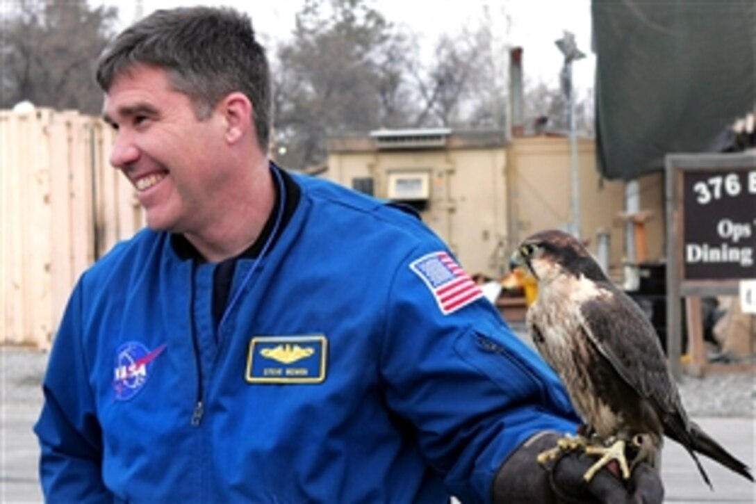 U.S. Navy Capt. Steve Bowen, a NASA astronaut, poses for a picture with Mustang, one of two falcons trained to keep birds away from the airfield on Manas Air Base, Kyrgyzstan, during a tour of the base, Jan. 28, 2009. The crew of the Space Shuttle Endeavour visited with airmen and local Kyrgyz school children during their two-day visit.