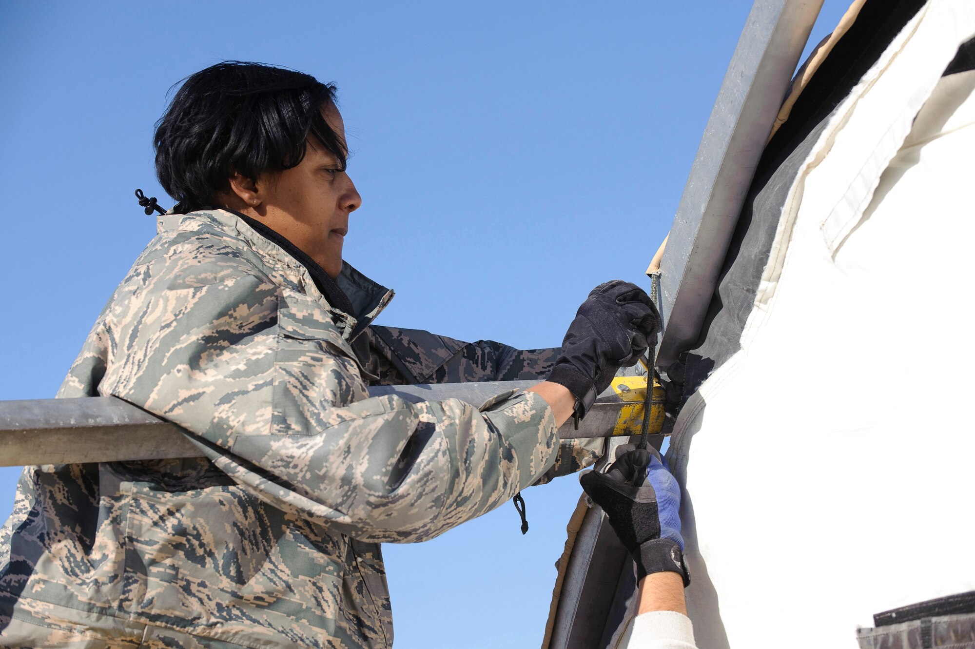 Master Sgt. Stephanie Nelson, Hospital Administrator with the 374th Medical Support Squadron, tightens the outside wall of a portable hospital tent during Expeditionary Medical Support Course (EMEDS) training with the U.S. Air Force School of Aerospace Medicine, Brooks City-Base, Texas Feb. 2. The tent build-up phase, during the first day of EMEDS gives 374th Medical Group personnel the skills required to deploy a basic EMEDS package within 24 hours of arriving at a deployed location. (U.S. Air Force photo/Steve Thurow)