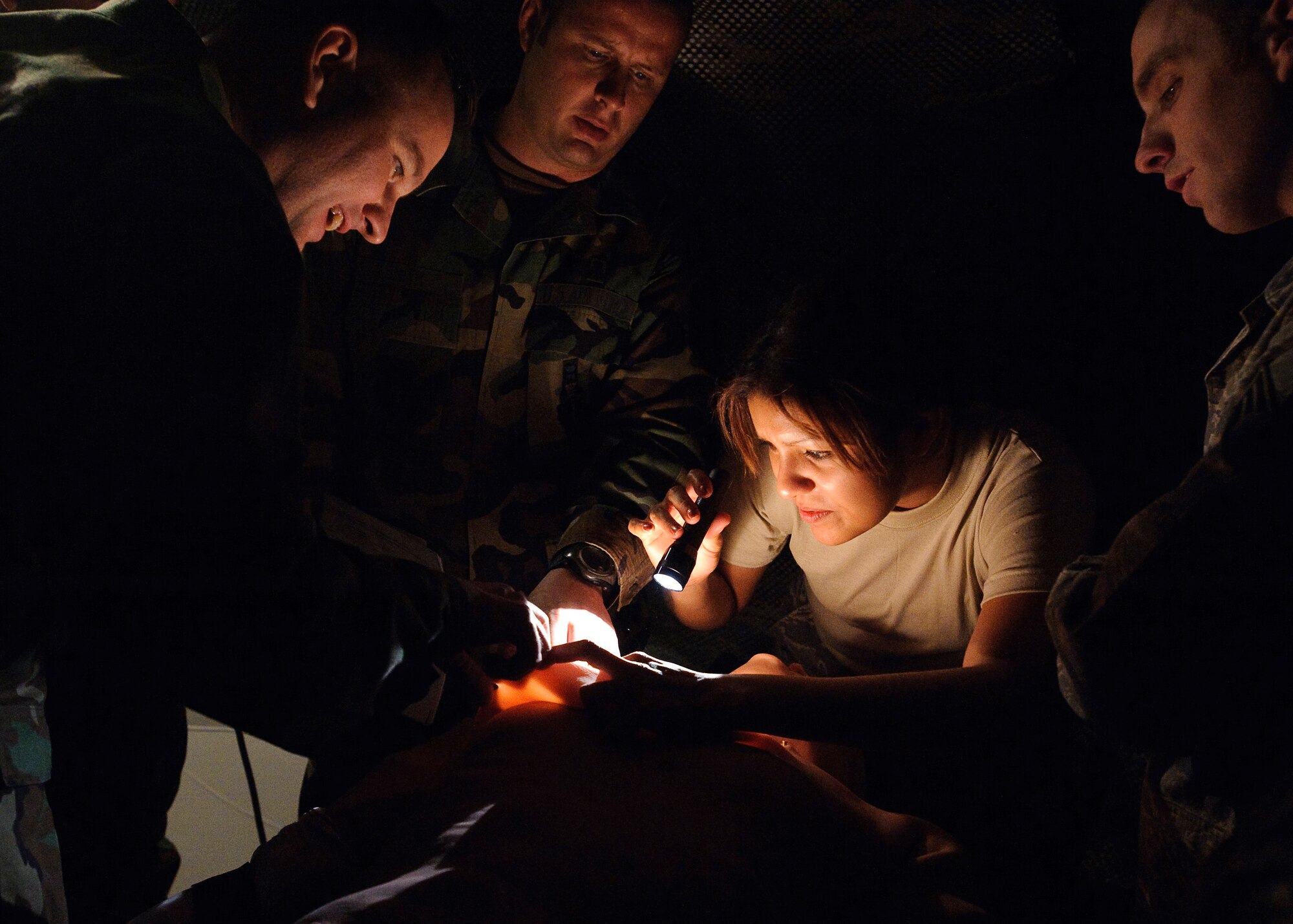 Col. Tim Robinette (left), 374th Medical Group commander, Yokota Air Base, Japan, reacts to the life-like response of a METI iStan after preforming a needle thoracentesis as  Staff Sgt. Yelena Enos (center), a medical technician assigned to the 375th Medical Operations Squadron at Scott AFB, IL., holds a light to aid vision in a simulated low-light combat situation. Students are introduced to the METI, iStan, patient simulator in preparation for the validation exercise during Expiditionary Medical Support Course training conducted by the US Air Force School of Aerospace Medicine, Brooks City-Base, TX, Feb. 3.  (U.S. Air Force photo/Steve Thurow)