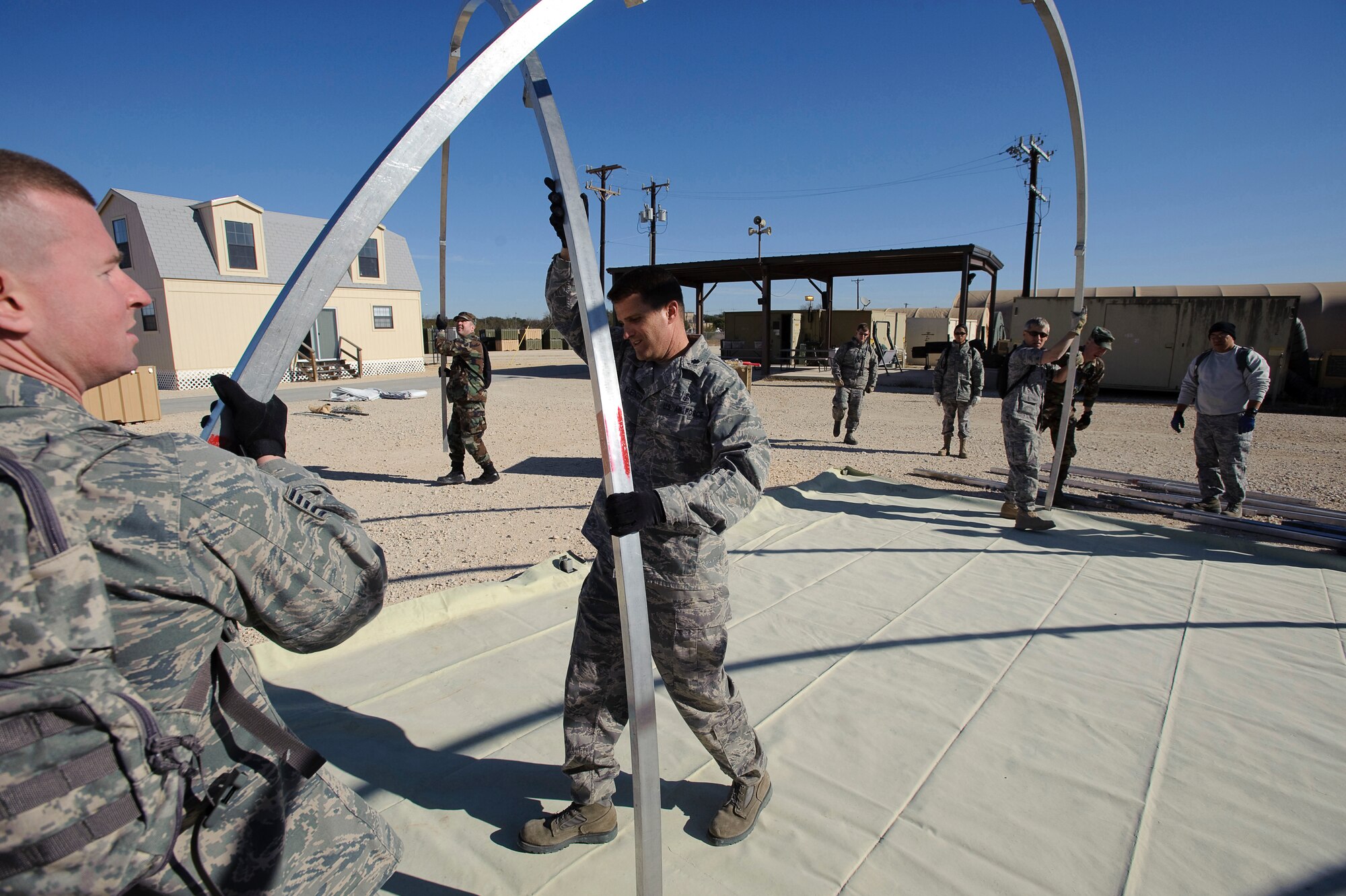 Lt. Col. Kelly Klein (center), commander of the  374th Medical Support Squadron, maneuvers a roof support for a portable hospital tent during Expeditionary Medical Support Course (EMEDS) training with the U.S. Air Force School of Aerospace Medicine, Brooks City-Base, Texas Feb. 2. The tent build up phase, during the first day of EMEDS training  gives 374th Medical Group personnel the skills required to deploy a basic EMEDS package within 24 hours of arriving at a deployed location. (U.S. Air Force photo/Steve Thurow)