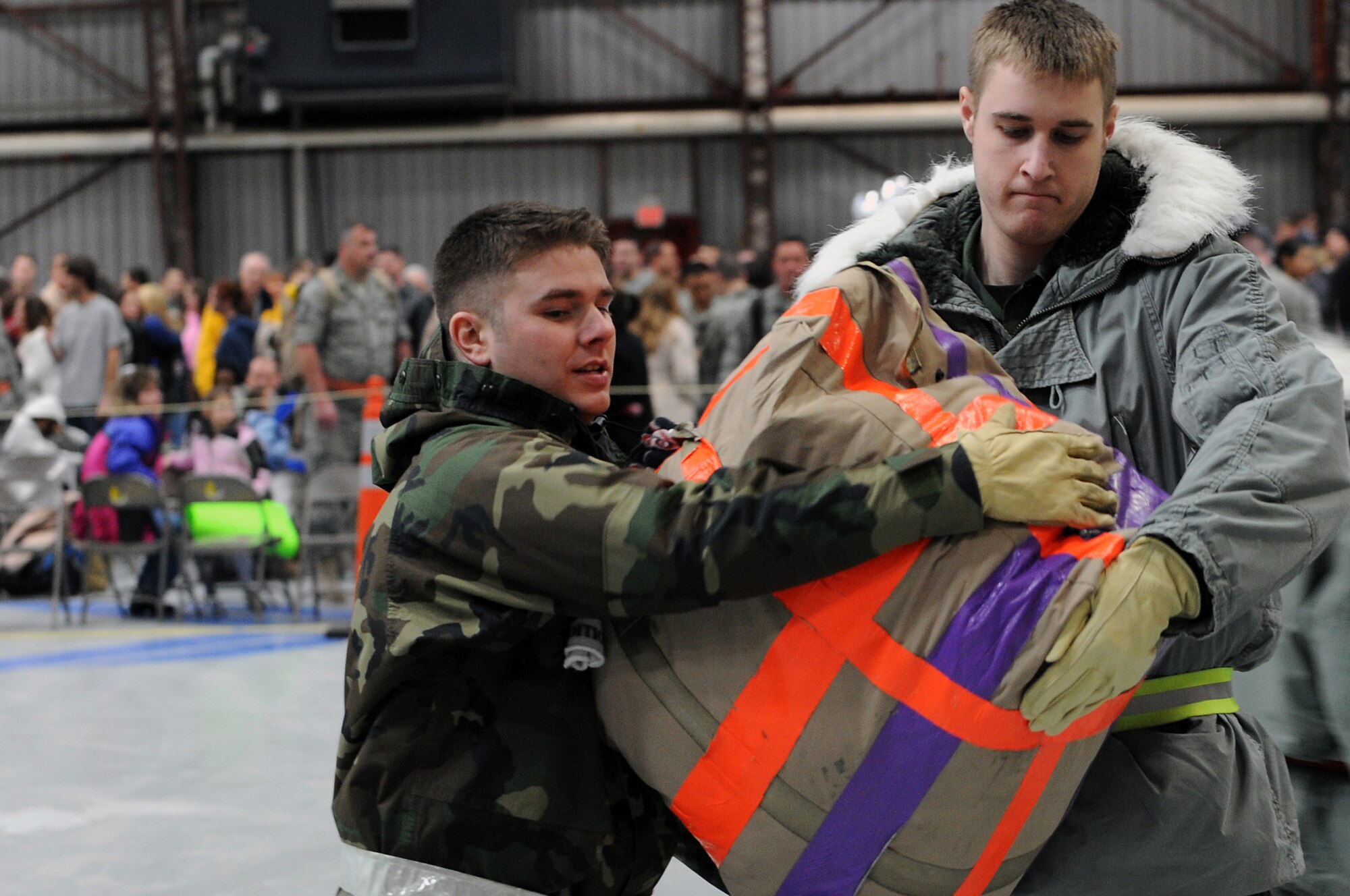 (Right) Airman 1st Class Derek Nash, 28th Communications Squadron computer systems operator, hands a bag to Airman 1st Class Peter Bourgeois, 28 CS radio maintenance journeyman, here, January 31. The Airmen volunteered to help unload the bags for those returning from their deployments. (U.S. Air Force photo/Senior Airman Marc I. Lane)