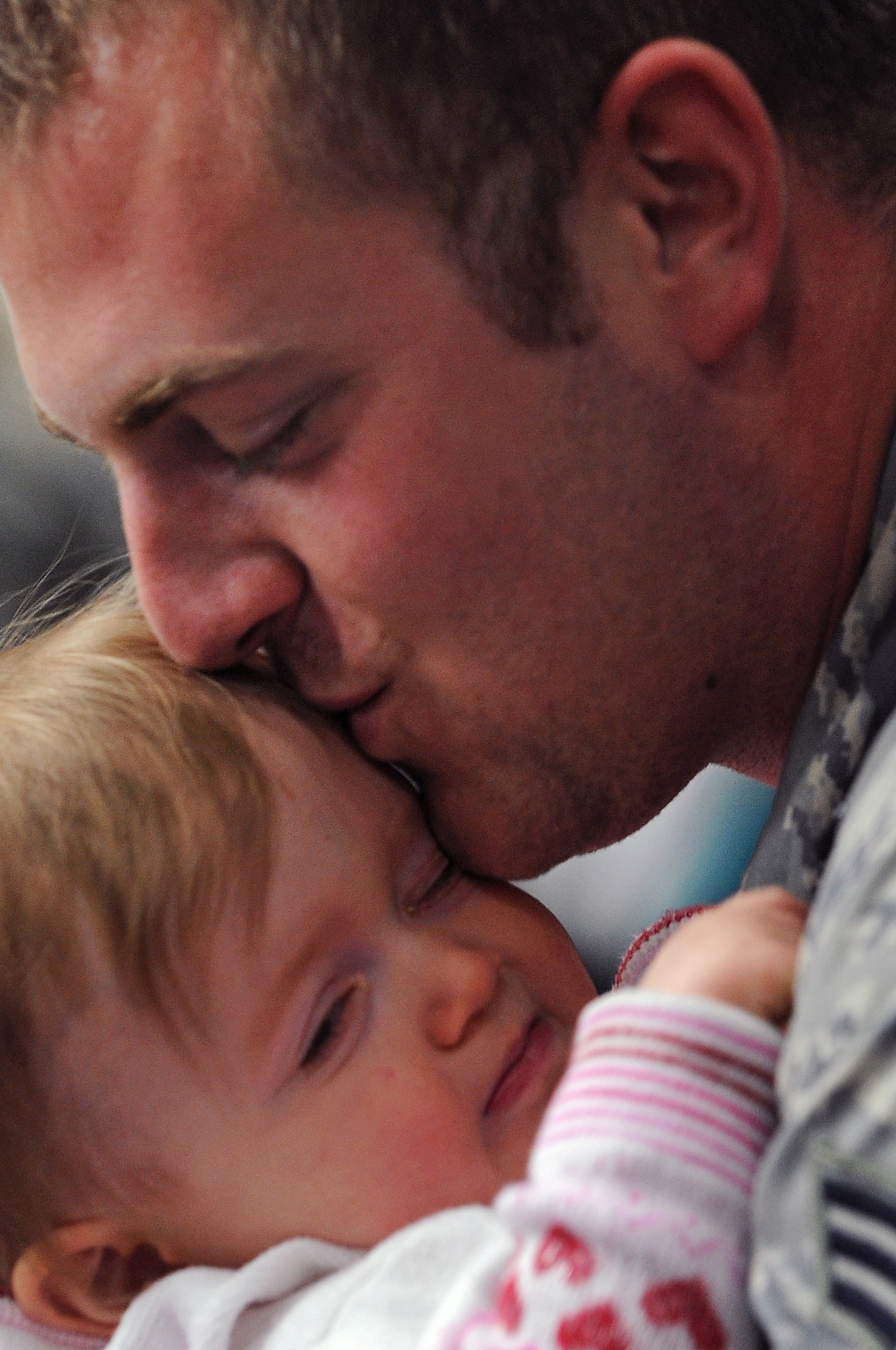 Senior Airman Mike Cunningham, 28th Aircraft Maintenance Squadron offensive avionics technician, kisses his daughter, Emma, here, January 31. Airman Cunningham was deployed for six months in support of Operations Iraqi and Enduring Freedom. (U.S. Air Force photo/Senior Airman Marc I. Lane)