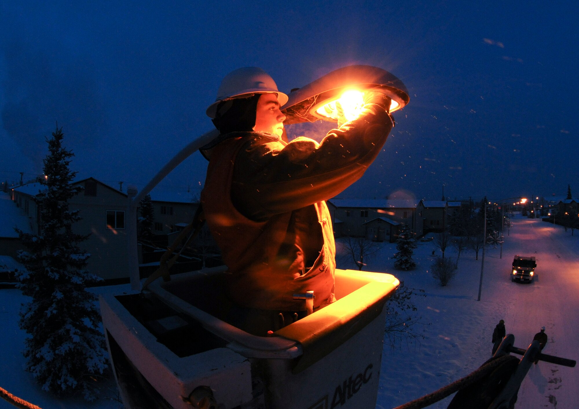 Senior Airman Scott Brown re-lamps a street light on Feb. 2, 2009 at Eielson Air Force Base, Alaska.   Airman Brown is hoisted by a 45- foot high reach bucket truck to access to the bulb.  The arctic environment and constant use during the winter months causes wear and tear on the street lamps.  (U.S. Air Force photo/Airman 1st Class Laura Max) 
