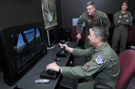 Maj. Gen. Gregory Feest, 19th Air Force commander, maneuvers himself through a simulation as Lt. Col. Chris Welborn, 563rd Flying Training Squadron commander, and Col. Jacqueline Van Ovost, 12th Flying Training Wing commander, look on. General Feest visited several areas of the 12th Flying Training Wing Jan. 29-30 to learn more about the wing and its Airmen. (U.S. Air Force photo by Joel Martinez)