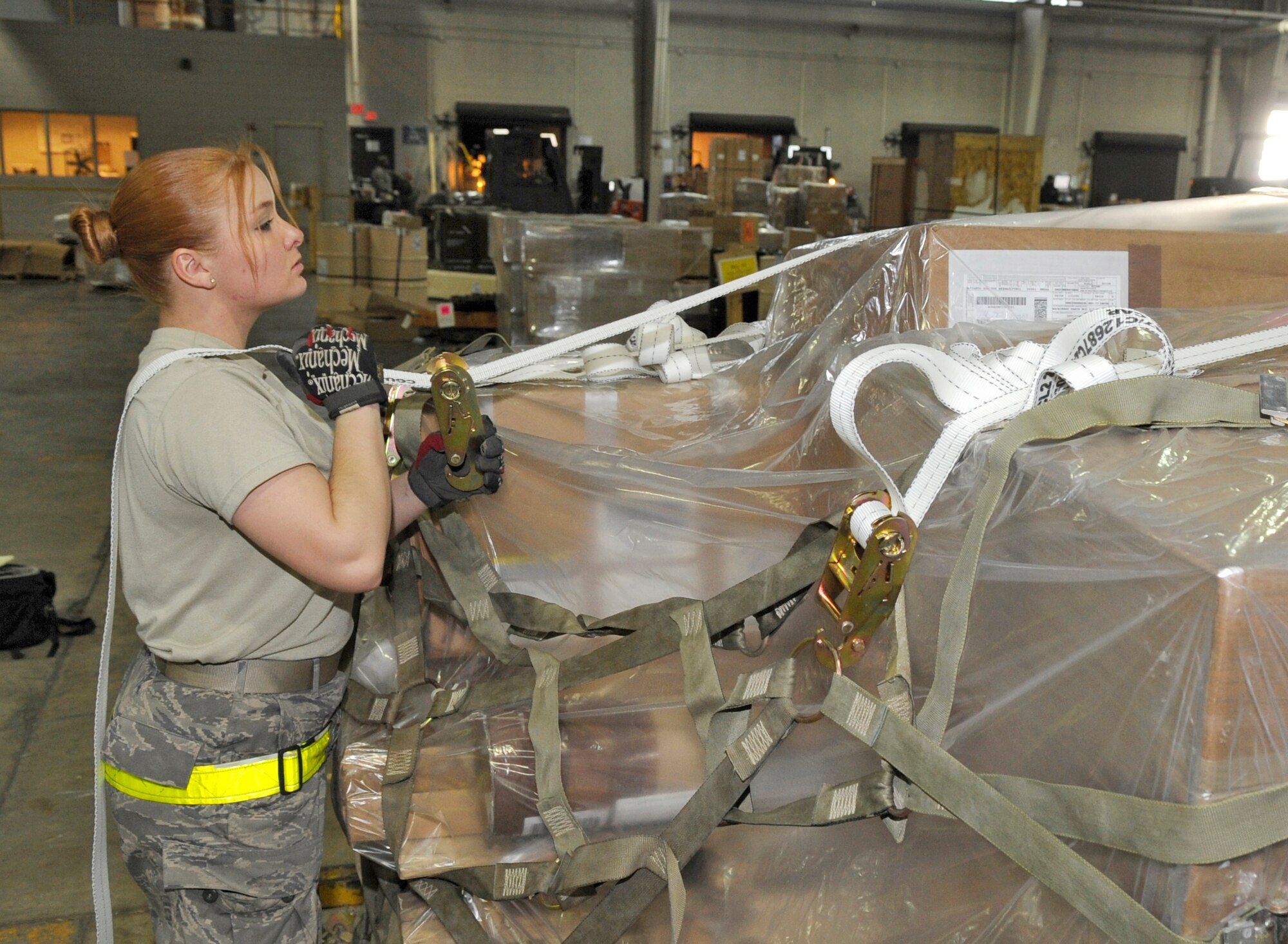 Airman Erica Hipwell, 305th Aerial Port Squadron air transportation apprentice, attaches a cargo strap to side netting in order to secure the top of a pallet Jan. 29. Pallets that aren't very high are secured with a cargo strap, which can hold up to 5,000 pounds. Seventy-five percent of all cargo leaving McGuire goes to Ramstein Air Force Base, Germany, before heading to its final destination in places like Iraq and Afghanistan. (U.S. Air Force photo/Carlos Cintron)