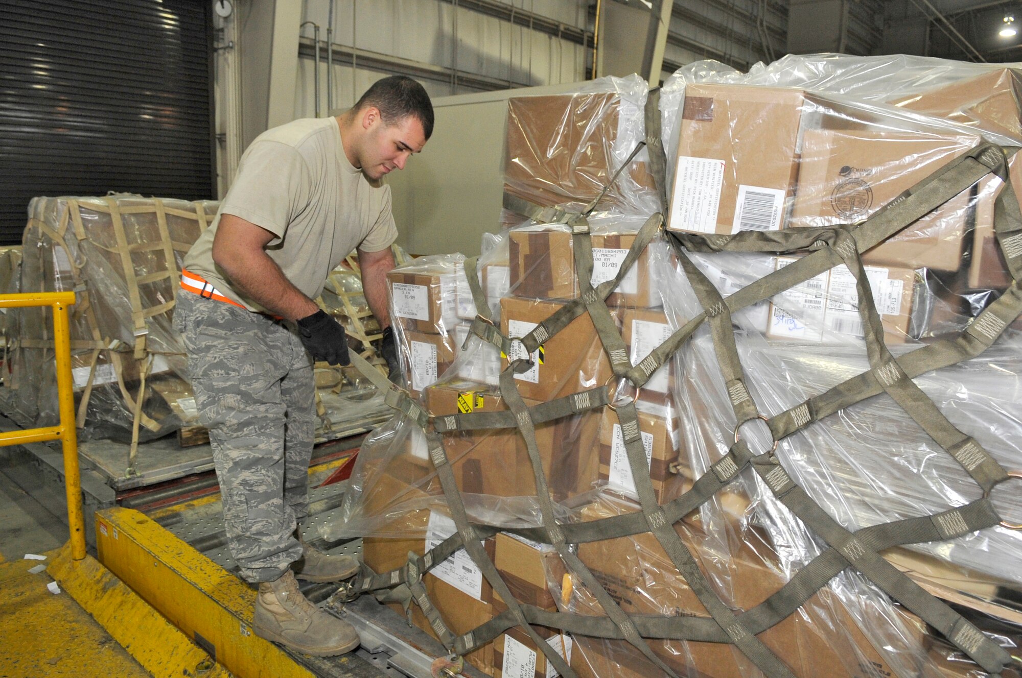 Senior Airman Ryan Ruffini, 305th Aerial Port Squadron air transportation journeyman, attaches two side nets to secure the cargo and pallet during transportation Jan. 29. The pallet pits can be lowered down in order to place netting over the top of pallets that are built up high. The height of each pallet is measured to make sure they meet height limitations of various aircraft configurations. (U.S. Air Force photo/Carlos Cintron)