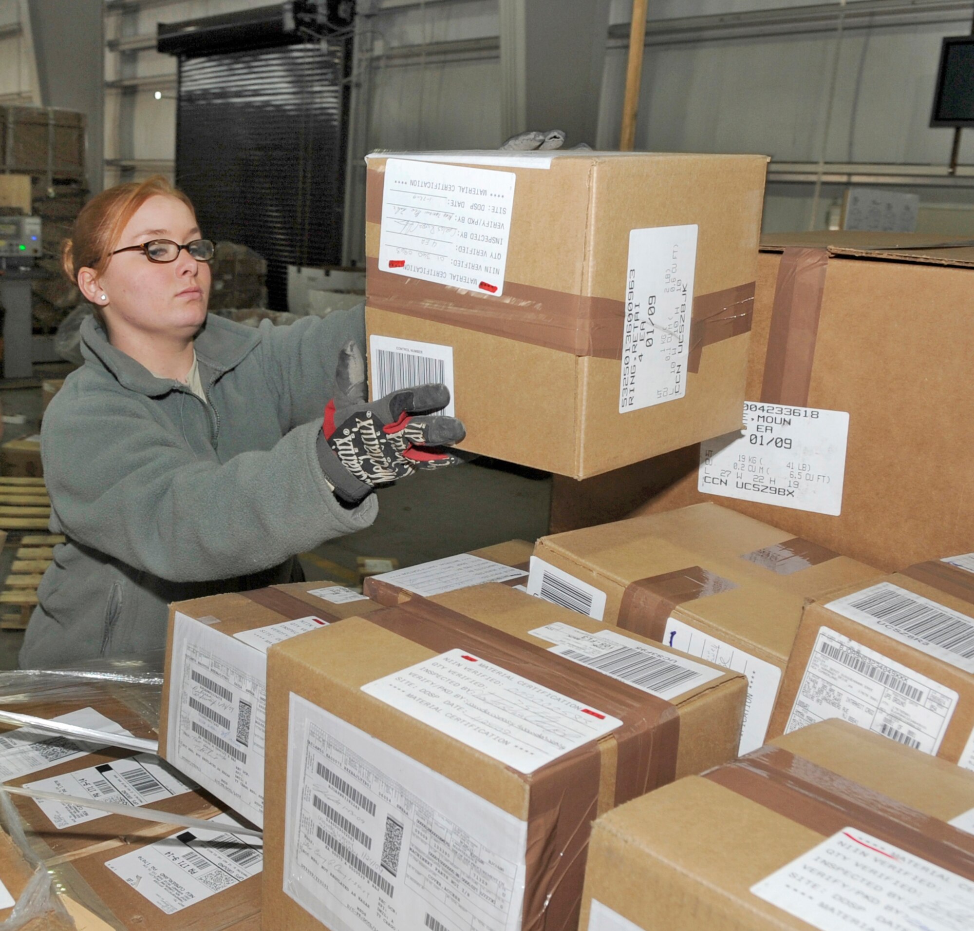 Airman Erica Hipwell, 305th Aerial Port Squadron air transportation apprentice, builds a cargo pallet at a pallet pit in the 305th APS warehouse Jan. 29. The warehouse features six pallet pits. Two pallets can be built up at each pit before being moved to the outside loading platform where they are eventually moved onto K-loaders. From there, the pallets are loaded onto various cargo planes such as the B-747, C-17, KC-10, C-5, and C-130. (U.S Air Force photo/Carlos Cintron)