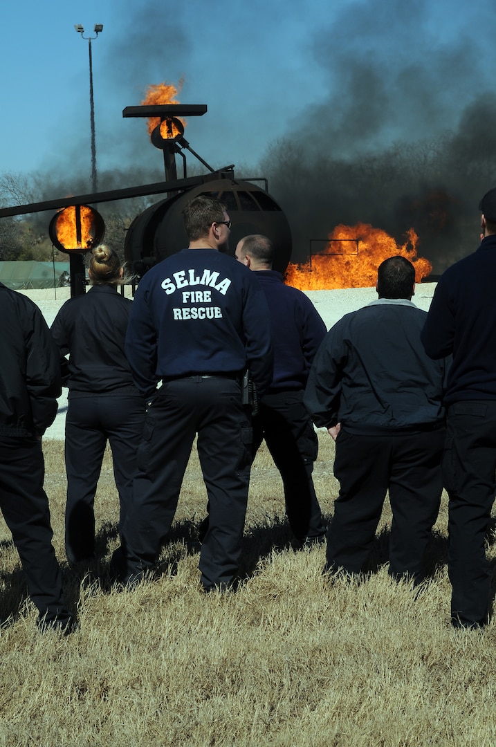 Fire department personnel from several local cities watch Randolph Fire Emergency Services personnel extinguish an aircraft fire during a training session Feb. 1. Several local fire departments visited Randolph to train on proper response procedures to downed 12th Flying Training Wing aircraft in the event one crashed in their city. (U.S. Air Force photo by Steve White)