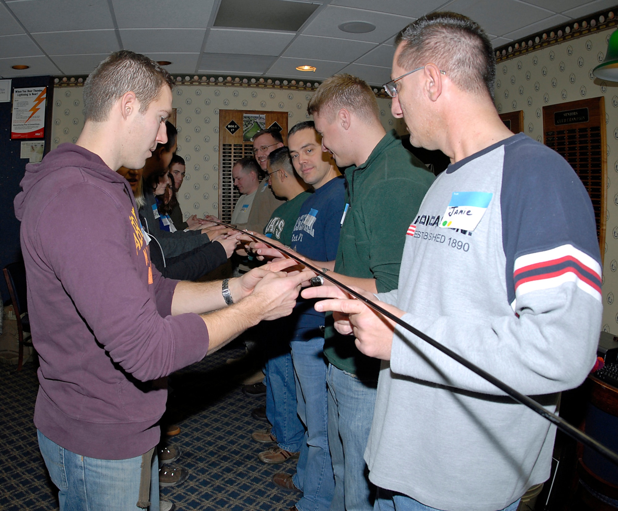 The Accelerated Leadership Class works as a team to lower a tent pole.  Each person must use only their two index fingers that must touch the pole at all times. This challenge exercised their communication and team work skills. (Air Force photo/ Roberta McDonald) 