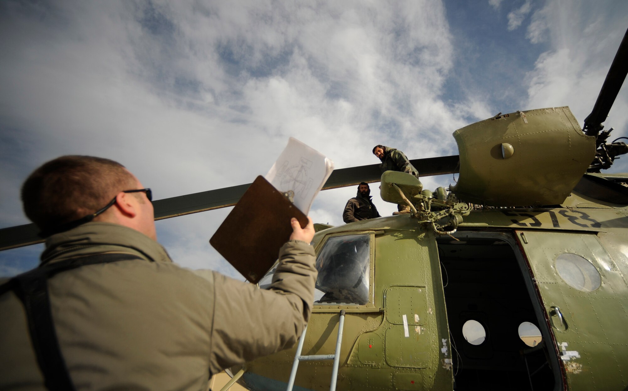 Air Force Master Sgt. Jacob Larsen from the 438th Air Expeditionary Advisory Group requests a form from Afghan Air Corps MI-17 helicopter mechanics  at a military installation in Kabul, Afghanistan on Jan. 22, 2009. (U.S. Air Force photo by Staff Sgt. James L. Harper Jr.)