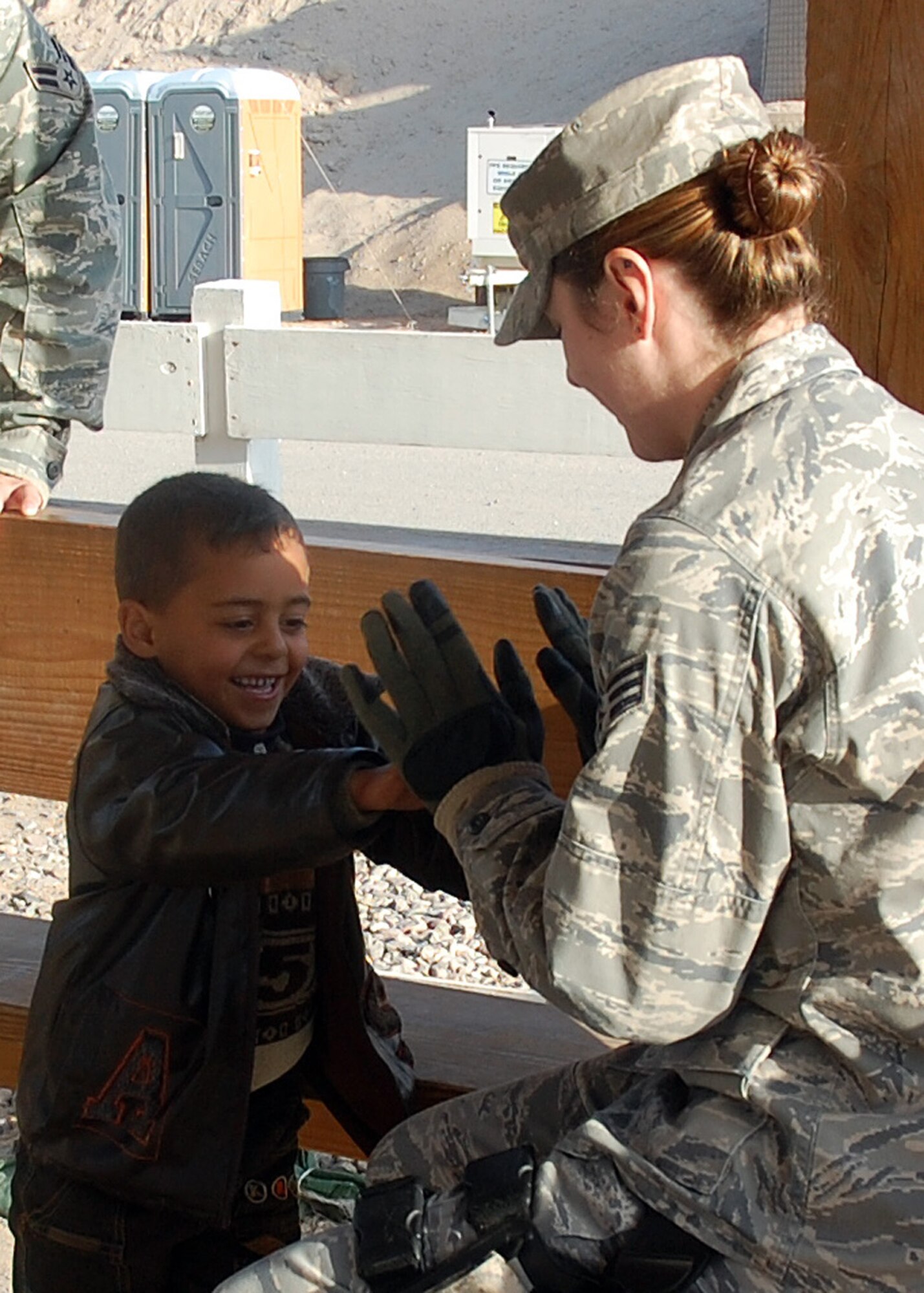 CAMP BUCCA, Iraq -- Senior Airman Tarann Earl, 887th Expeditionary Security Forces Squadron, plays with an Iraqi child Jan. 27 at Camp Bucca, Iraq, while they wait for transport to the detainee visitation center. The 887th ESFS provides security and transportation to the center for Iraqis who are allowed to visit daily with detained family members held at the Theater Internment Facility. (U.S. Air Force photo by Capt. Angelic Dolan)