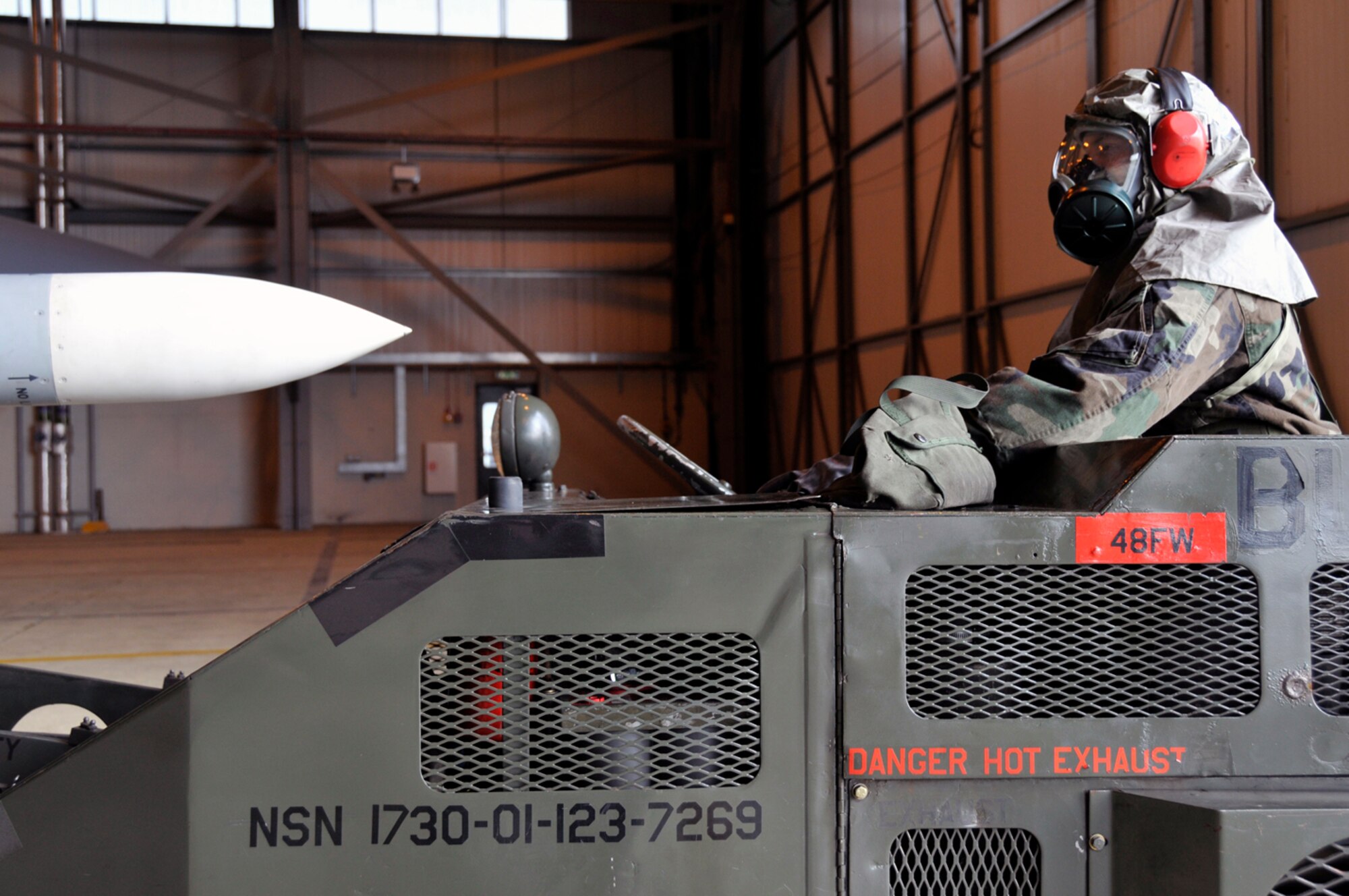Airman 1st Class Eric McCain , 48th Aircraft Maintenance Squadron weapons load crew member, stands by on the jammer while his other crew members prepare the AIM-120 for loading Jan. 27 at RAF Lakenheath, England. The load crew was being qualified on loading munitions in MOPP 4 for their crews certification training. (U.S. Air Force photo by Airman 1st Class Perry Aston)