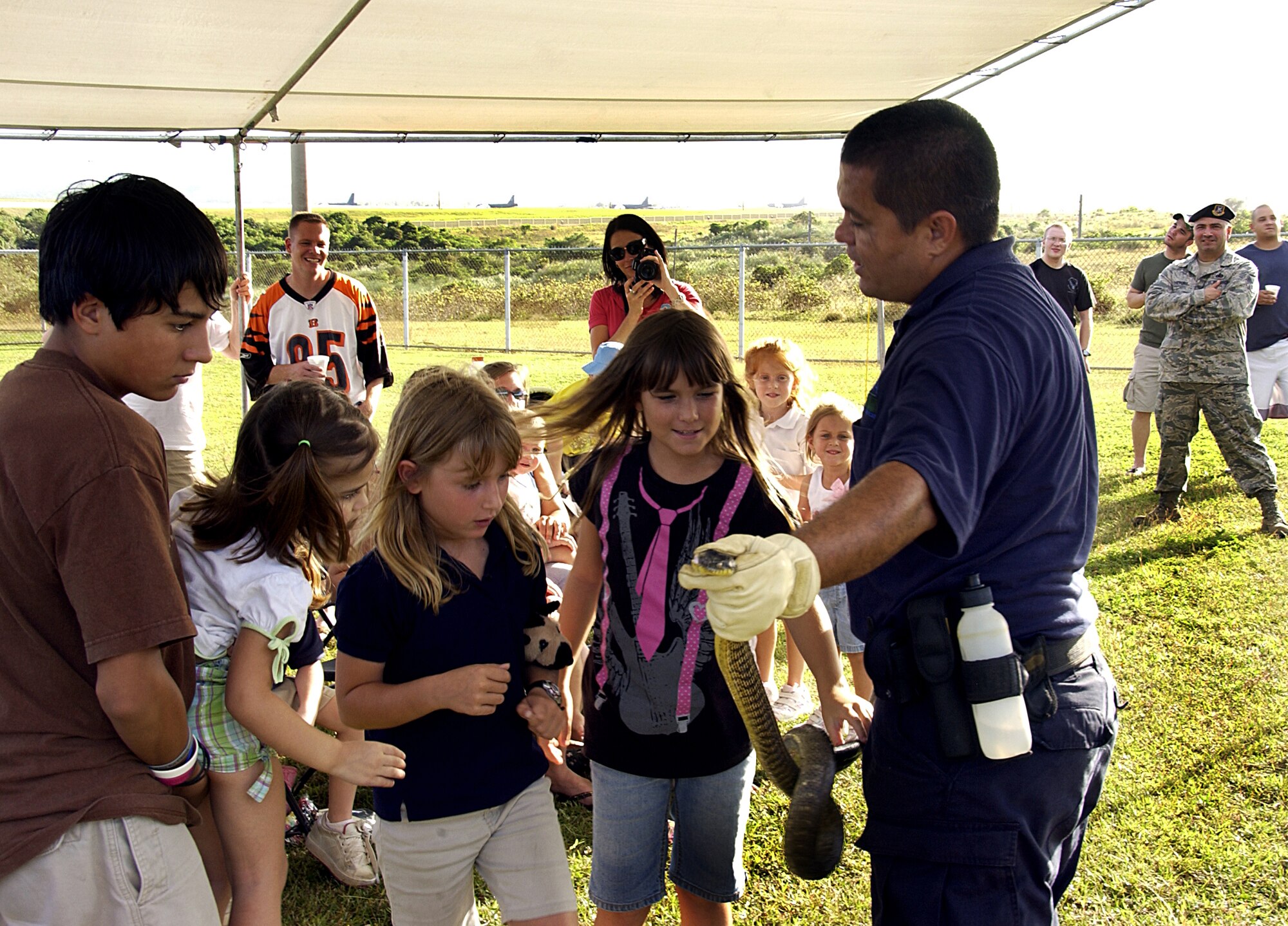 ANDERSEN AIR FORCE BASE, Guam -- Mr. Tony Pangelinan, the U.S. Department of Agriculture for Andersen area K9 trainer, holds a brown tree snake while members of the crowd come to touch and view the snake Feb. 2 at the first military working dog competition hosted by the 36th Security Forces Squadron here. Mr. Pangelinan and USDA working dog Shaun were one of the five teams to compete in this year's event. (U.S. Air Force photo by Airman 1st Class Carissa Wolff)                            