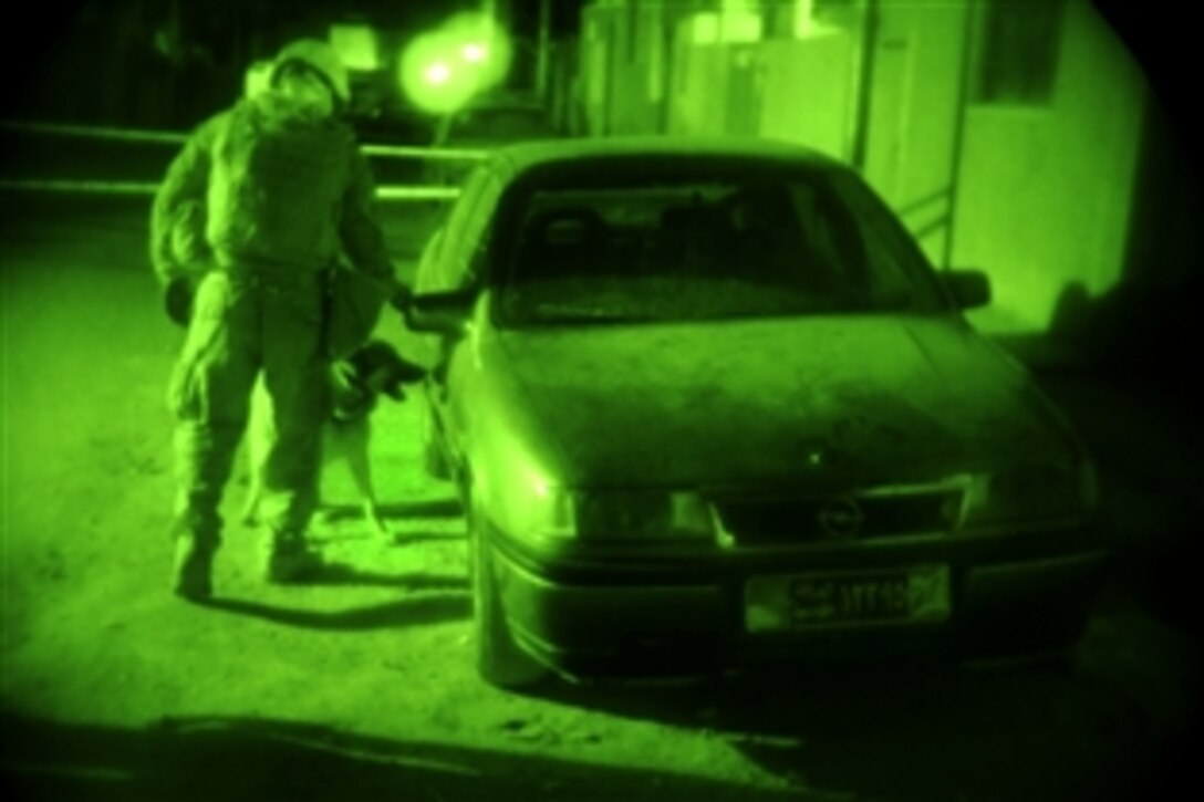As seen through a night-viewing device, U.S. Marine Corps Staff Sgt. Chris Willingham directs his military working dog, Lucca, to search a car parked near an Iraqi election site for explosives in Diwaniyah, Iraq, Jan. 30, 2009. Willingham is assigned to the 4th Infantry Division's Headquarters Company, 2nd Special Troops Battalion, 2nd Brigade Combat Team.