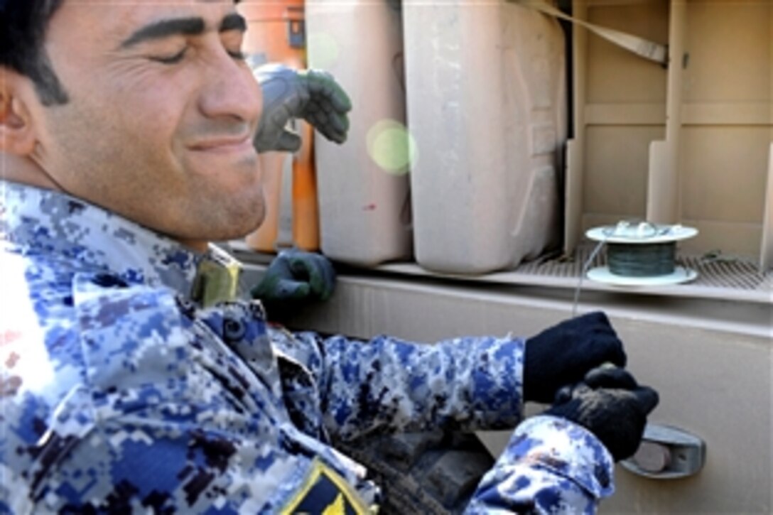 An Iraqi National Police officer pulls the detonation trigger from a safe location during a class on how to deal with improvised explosive devices taught by U.S. soldiers in the Doura district, Baghdad, Jan. 22, 2009. The U.S. soldiers are assigned to 192nd Battalion, 752nd Explosive Ordnance Disposal Company.