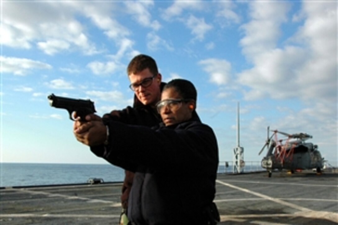 U.S. Navy Petty Officer 3rd Class Joseph Roverano teaches Petty Officer 1st Class Carlene Mart proper gun control during live-fire, small-arms qualifications aboard amphibious command ship USS Mount Whitney, under way in the Mediterranean Sea, Jan. 31, 2009.