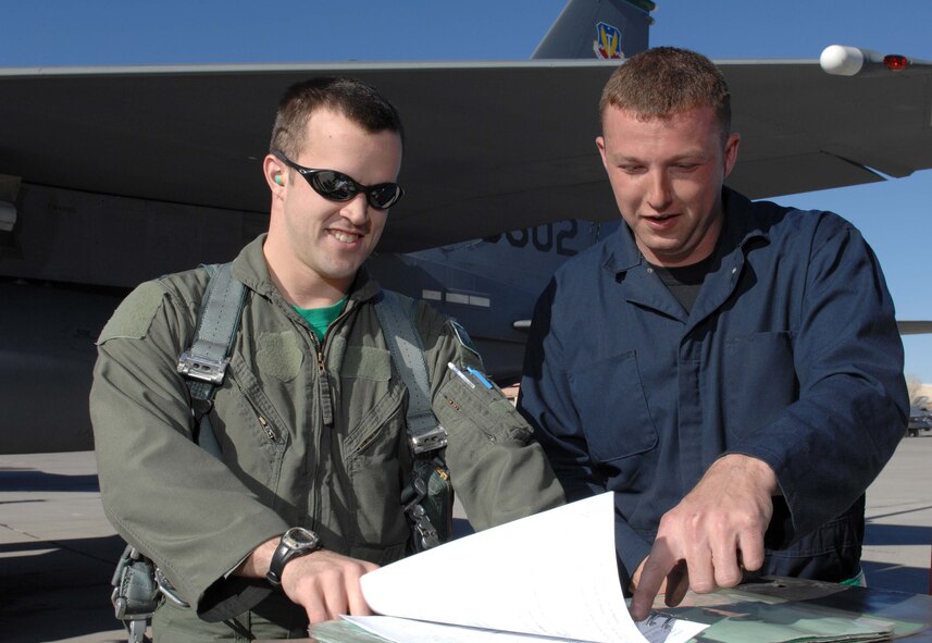 Captain Prichard Keely, an F-15E Strike Eagle pilot assigned to the 333rd Fighter Squadron, Seymour Johnson Air Force Base, N.C., reviews aircraft forms with Senior Airman James Steffes, an F-15E Strike Eagle crew chief assigned to the 4th Aircraft Maintenance Unit, after a training mission during Red Flag 09-2 at Nellis AFB, Nev., Jan. 30. Red Flag is a multi-national exercise providing a realistic environment to practice combat scenarios. The experience gained during the exercise is vital to the survival of air crews in combat. (U.S. Air Force photo/Senior Airman Larry E. Reid Jr.)