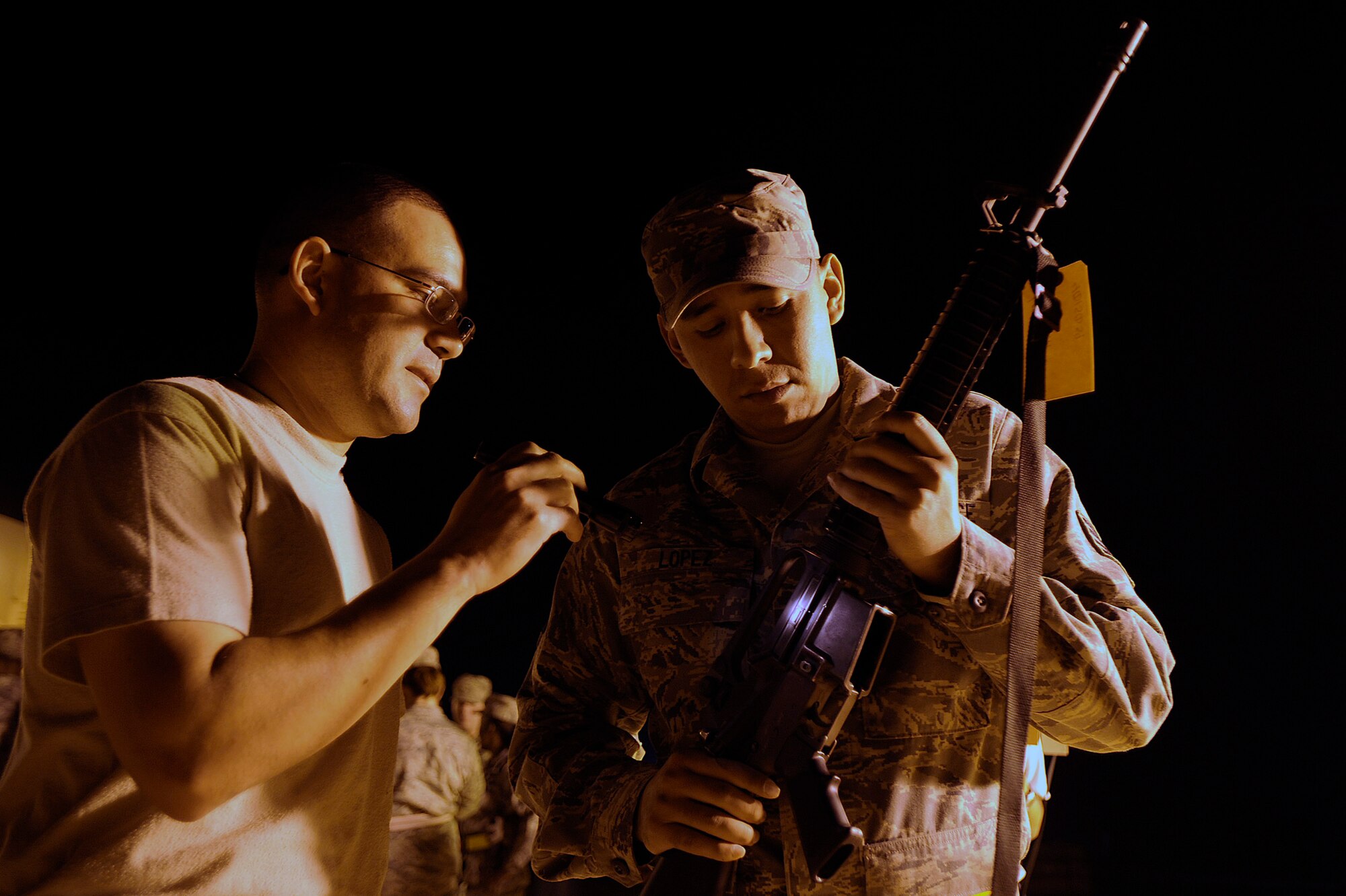 Tech. Sgt. Chris Atkinson shows Staff Sgt. Joseph Lopez the dust cover on his M-16 rifle during a force protection arming drill at Joint Base Balad, Iraq. Beginning with air and space expeditionary force cycle 7 and 8 in January and February, more than 3,000 deploying Airmen will get their weapons from the person they are replacing within the U.S. Central Command area of responsibility instead of bringing weapons with them from their home stations. A U.S. Air Forces Central weapons prepositioning initiative will save the service $1.2 million every four months and will make travel to and from the area of responsibility easier for deploying Airmen by reducing the amount of baggage they need to bring. (U.S. Air Force photo/Airman 1st Class Jason Epley) 
