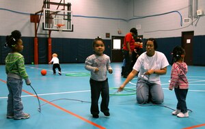 Lyvonnia Hyche teaches children how to jump rope in the Youth Programs Center gym Feb. 3. Once a week, providers get together at the Youth Programs gym for indoor play. Mrs. Hyche is a family child care provider. (U.S. Air Force photo/Airman Ian Hoachlander)