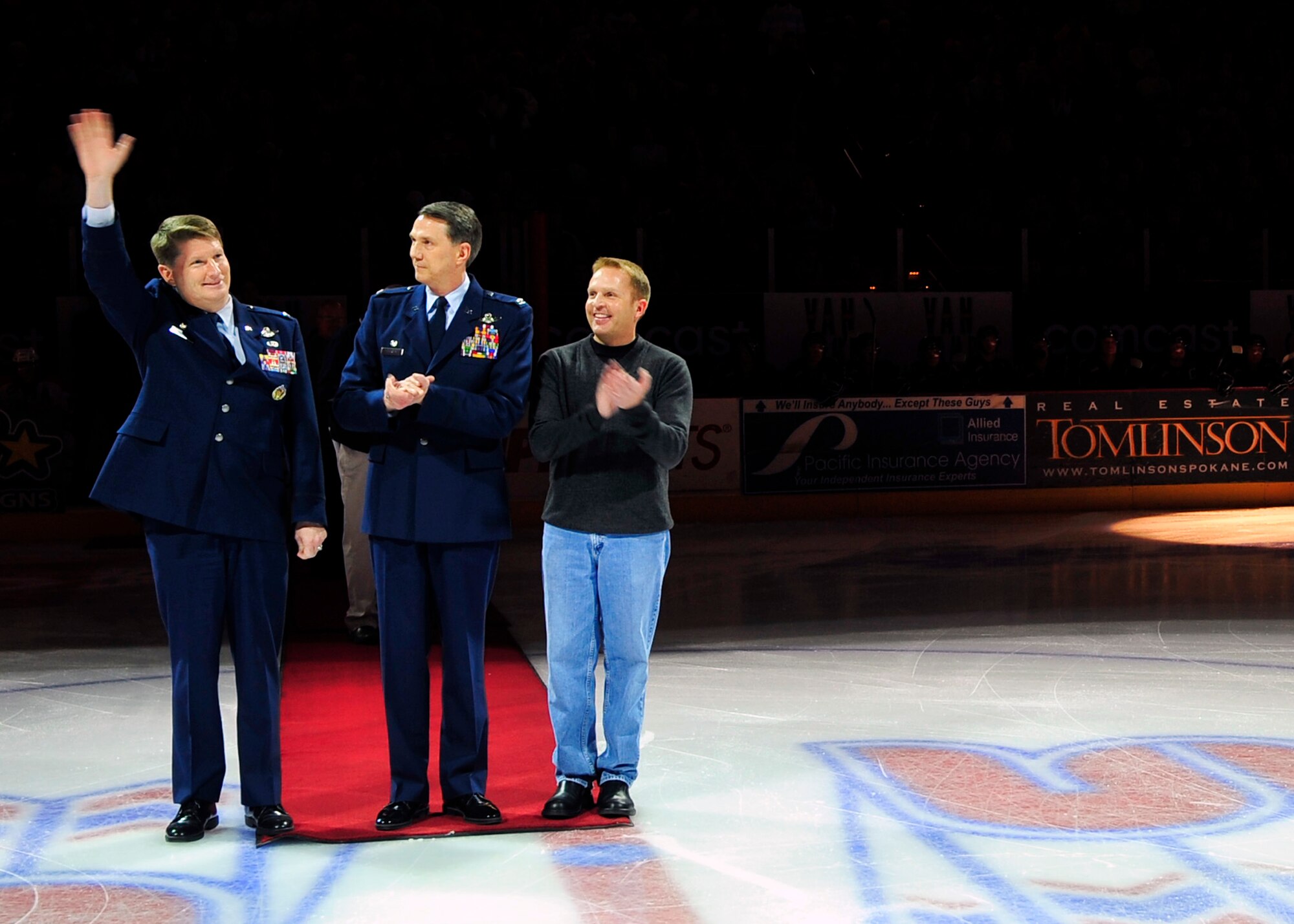 Col. Robert Thomas, 92nd Air Refueling Wing commander Fairchild Air Force Base, accompanied by Col. Gregory Bulkley, 141st Air Refeuling Wing Air National Guard commander Fairchild Air Force Base, and Cola Cola representative, Jamie Rippingler, waves to the crowd during the Spokane Chiefs Military Appreciation Night hockey game at the Spokane Arena Jan. 31. (U.S. Air Force photo / Airman 1st Class Melissa L. Barnett)